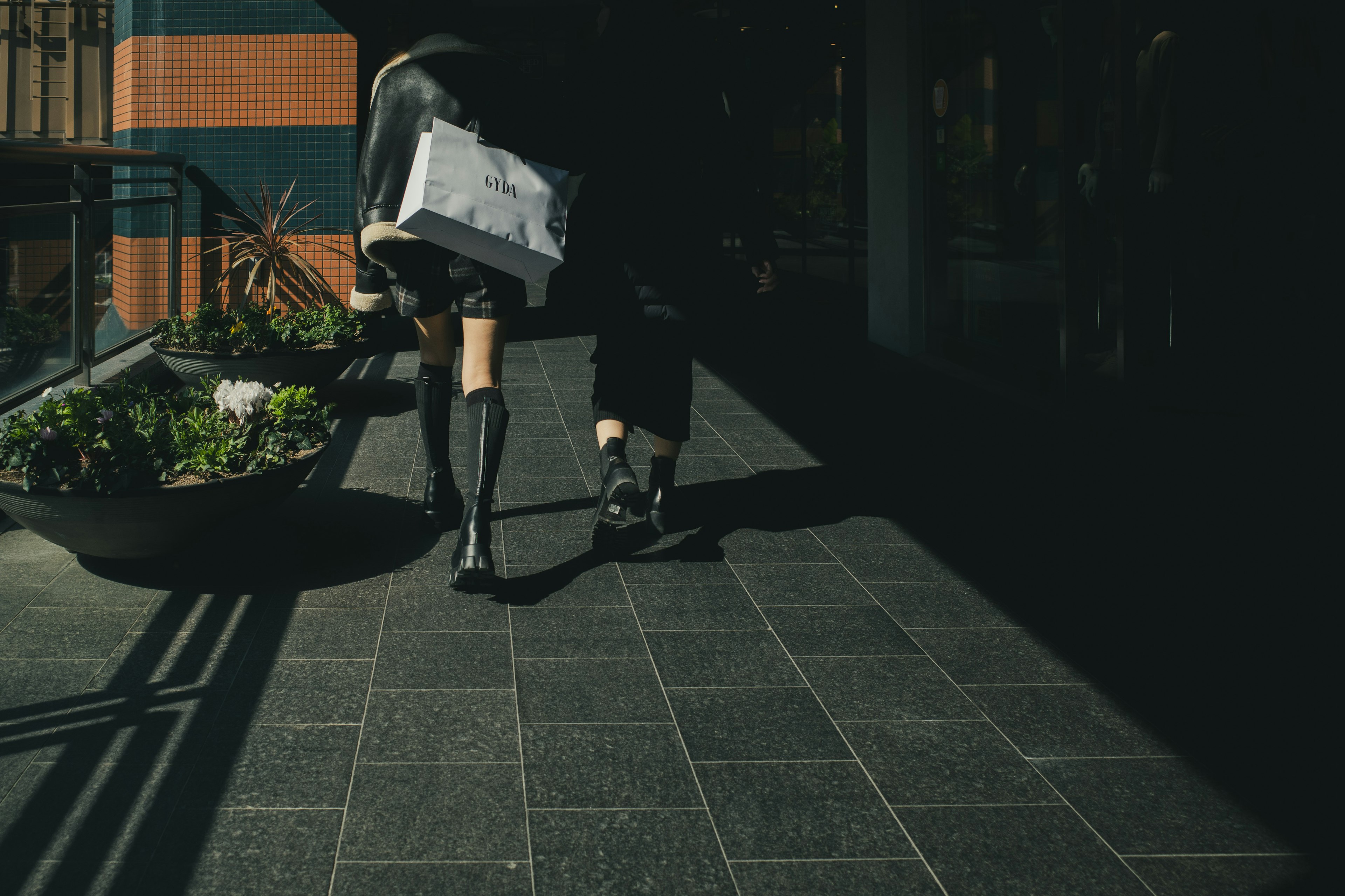 A woman walking with a shopping bag wearing black stockings and boots