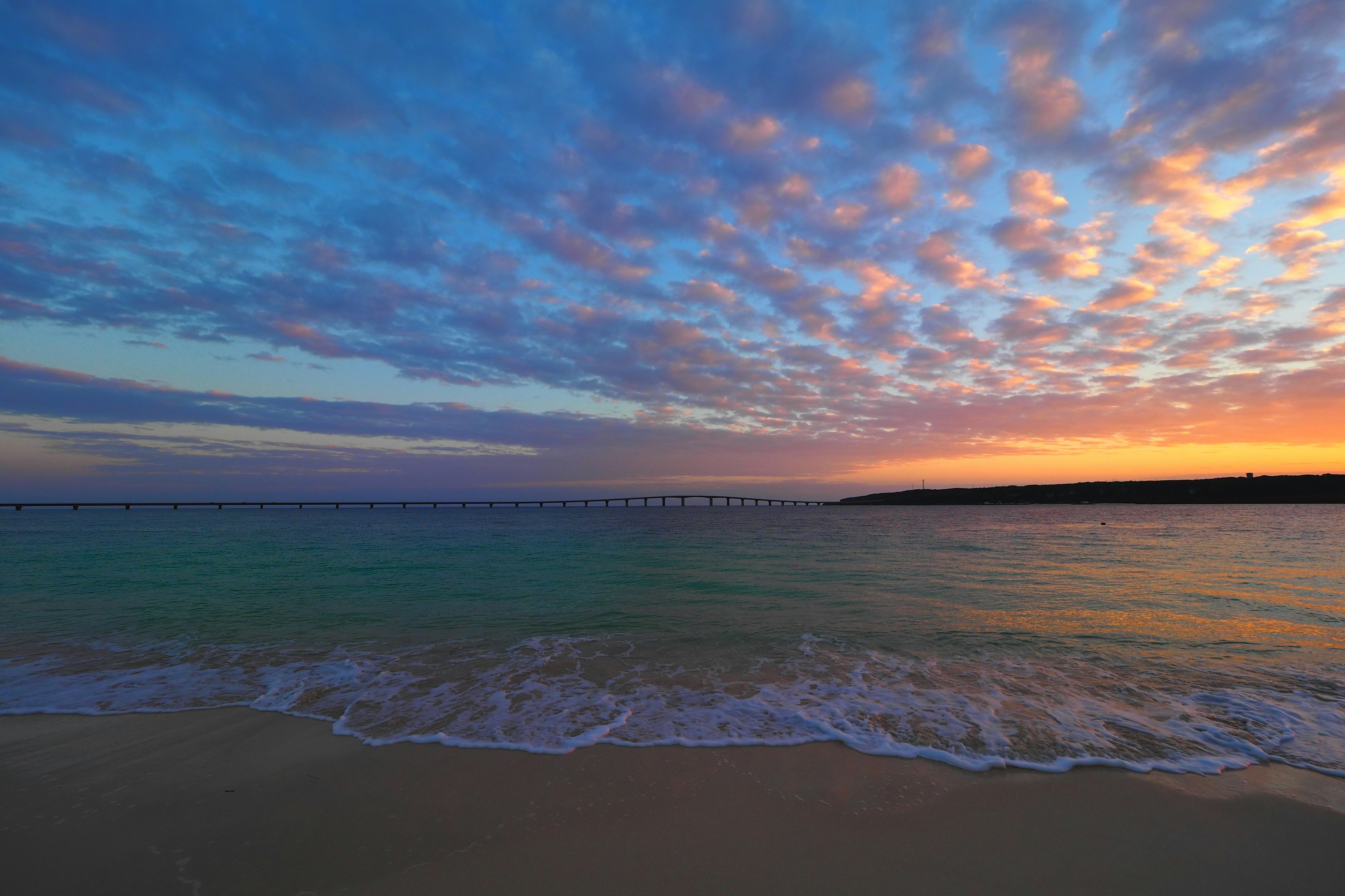 Scène de plage magnifique au coucher de soleil avec des nuages colorés dans le ciel