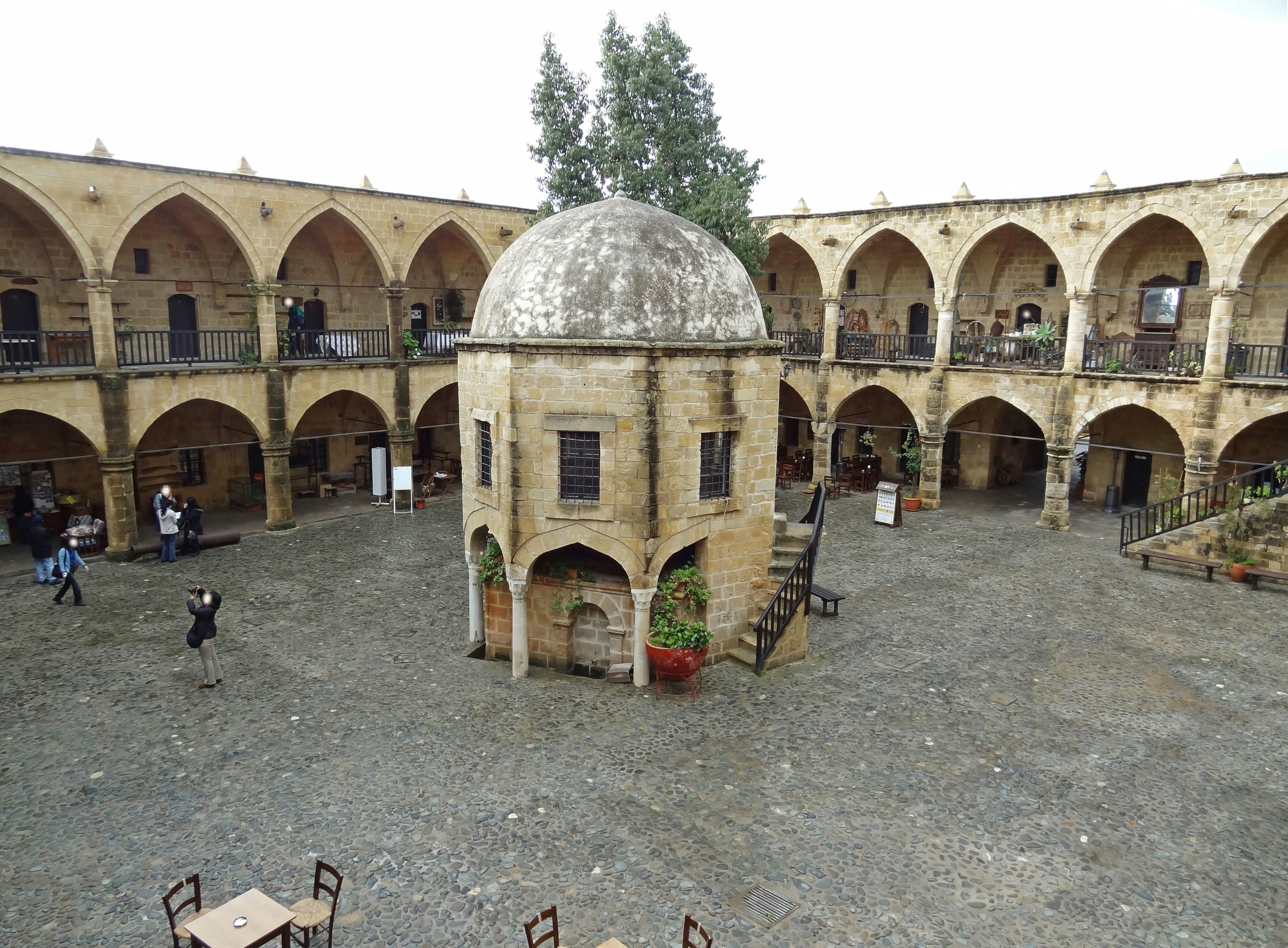 Historical courtyard featuring arched corridors and a central dome structure