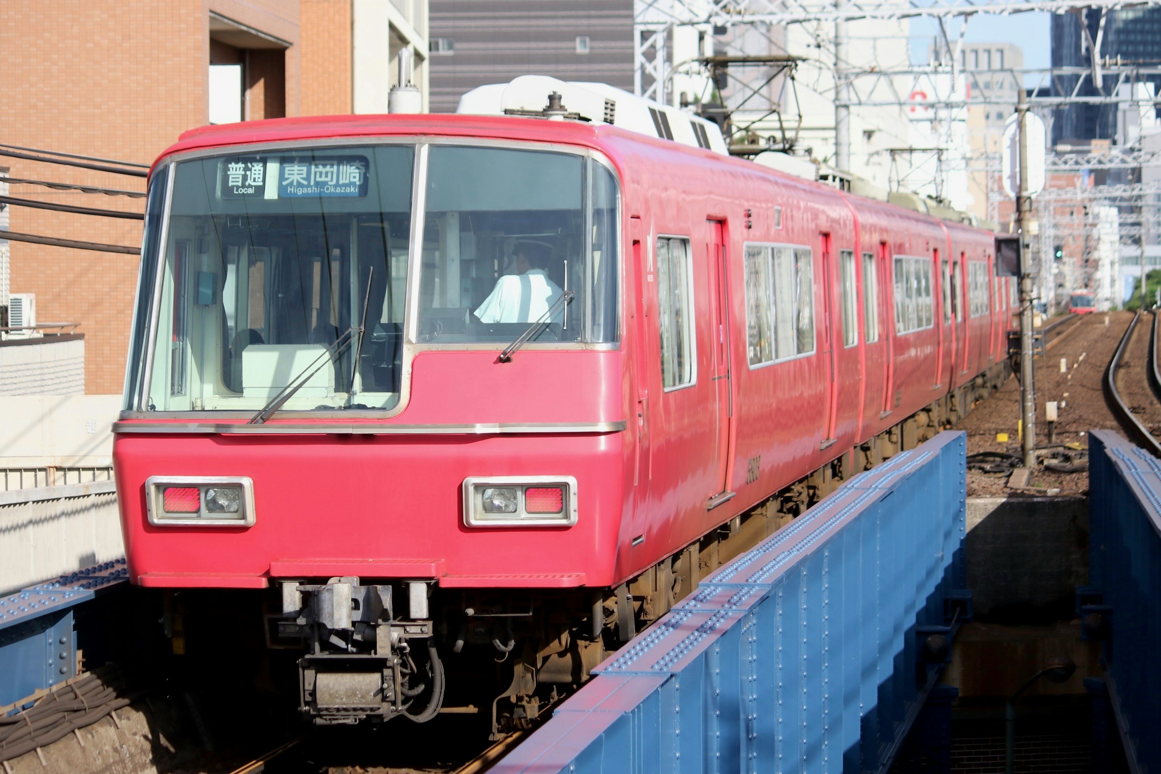 A red train on an elevated track in an urban setting