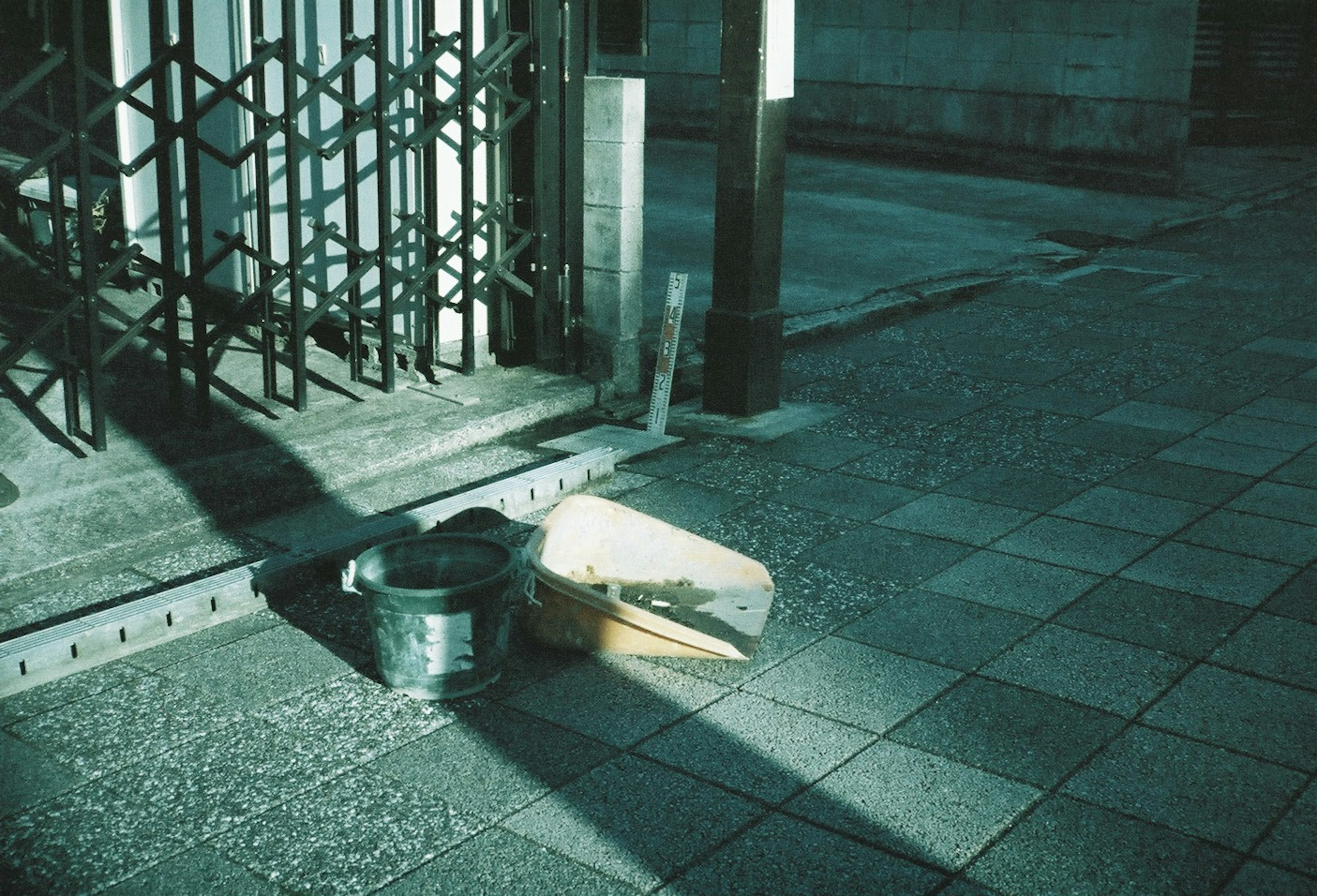 Imagen de un cubo de metal y una caja de cartón en una calle poco iluminada