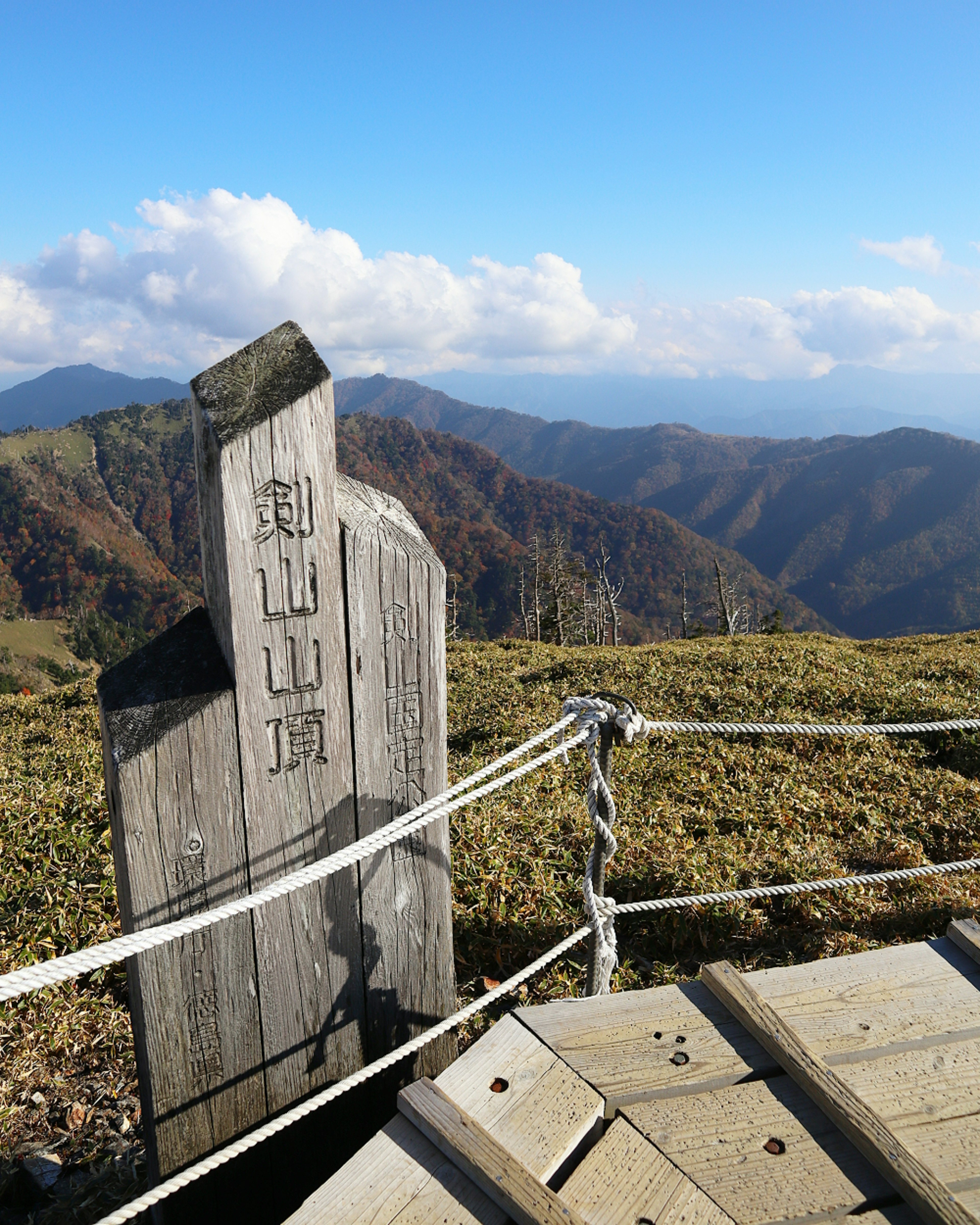 山の頂上にある木製の標識と美しい山々の風景