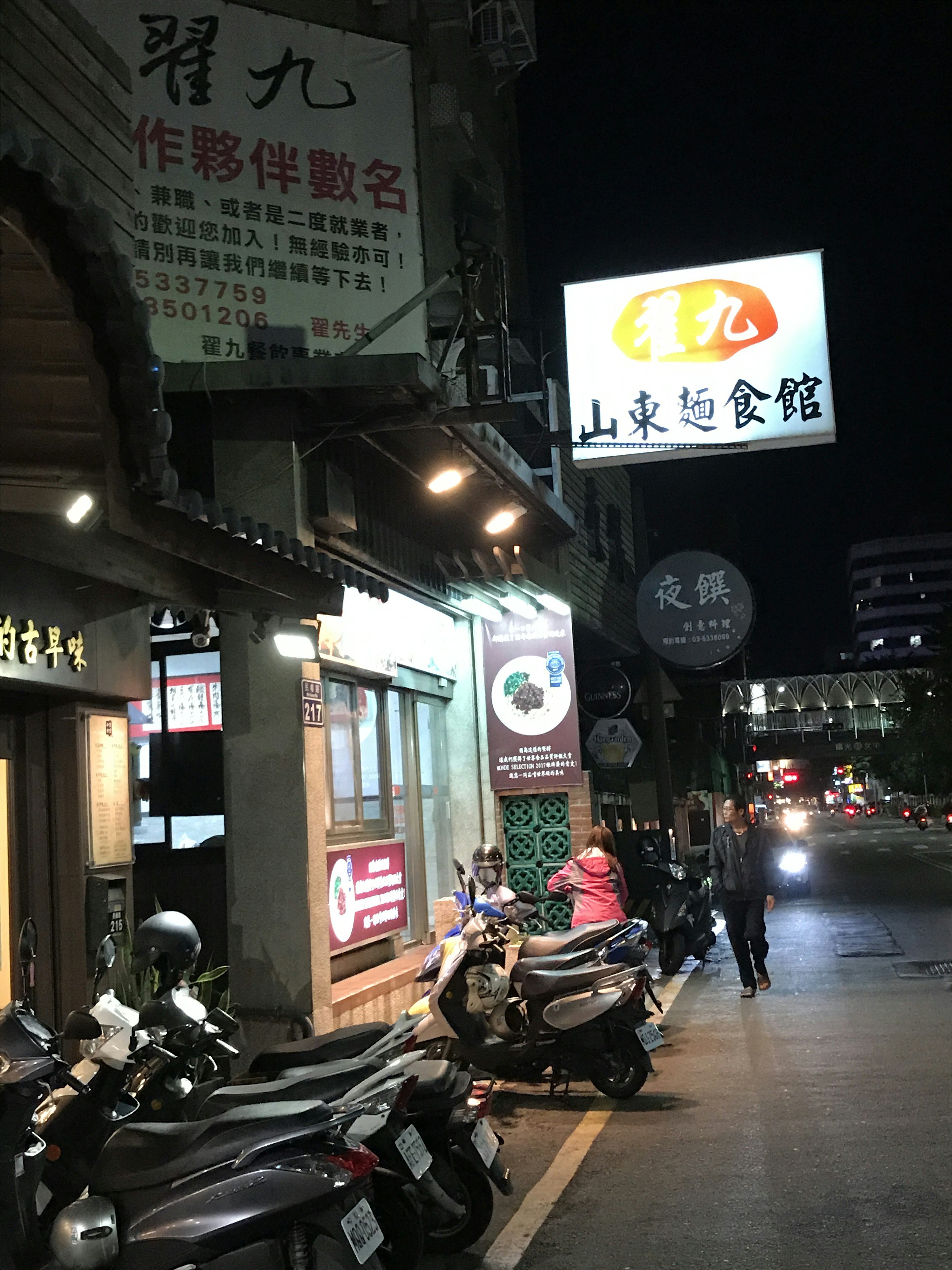 Tanda restoran di jalan malam dengan skuter terparkir