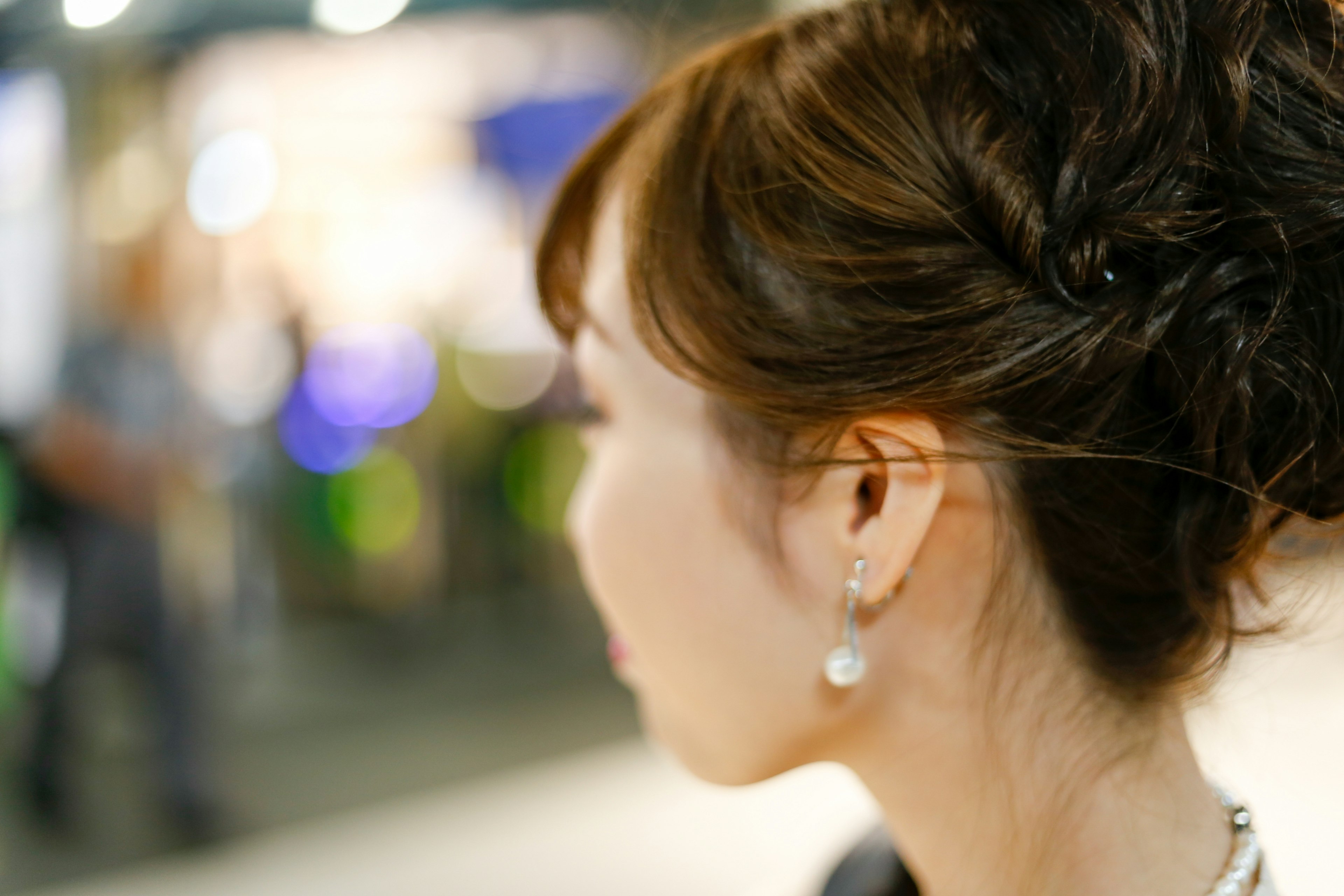 Foto wanita dilihat dari belakang dengan rambut diikat dan anting mutiara