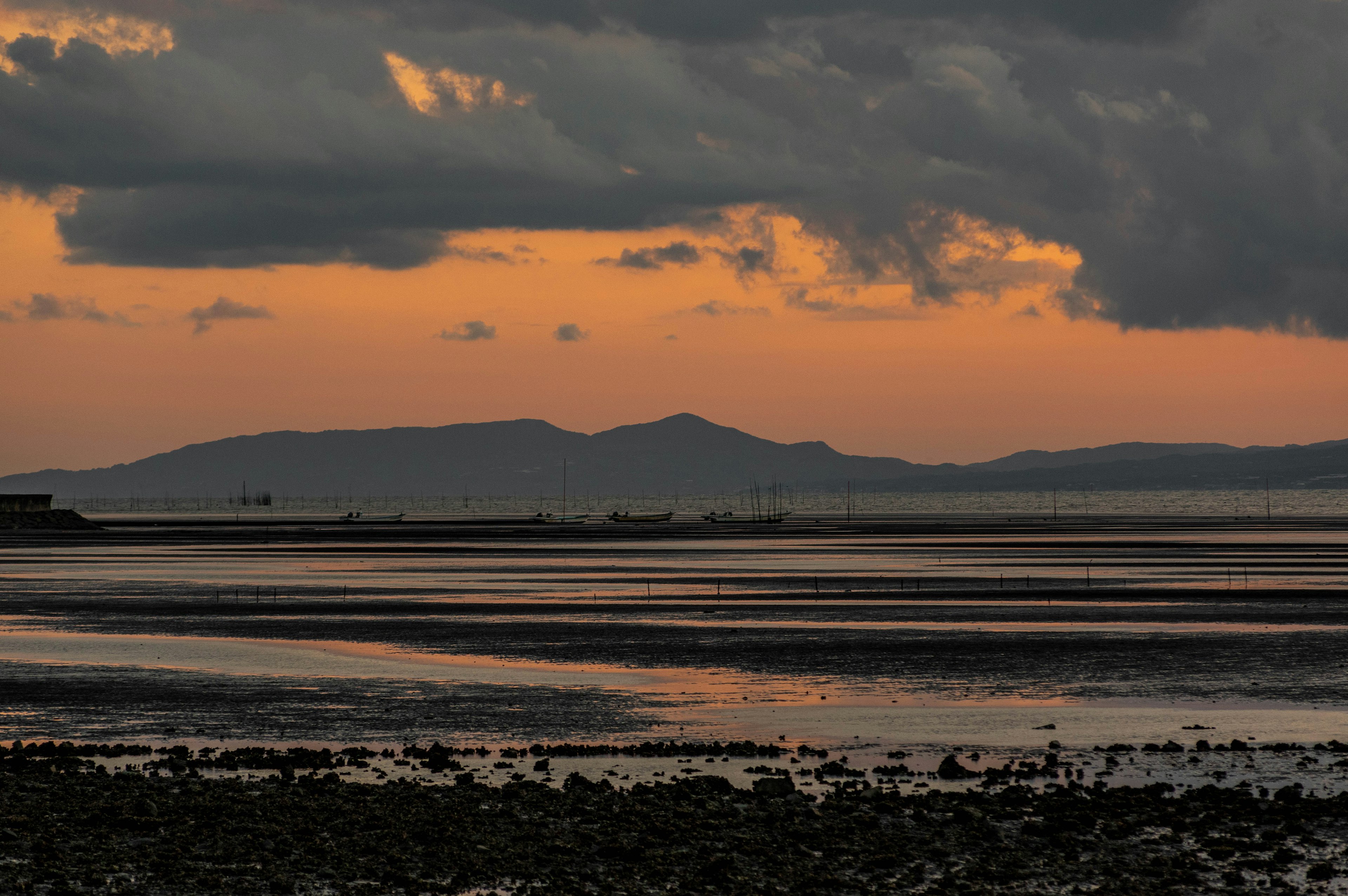 Coastal landscape at sunset with low clouds and distant hills