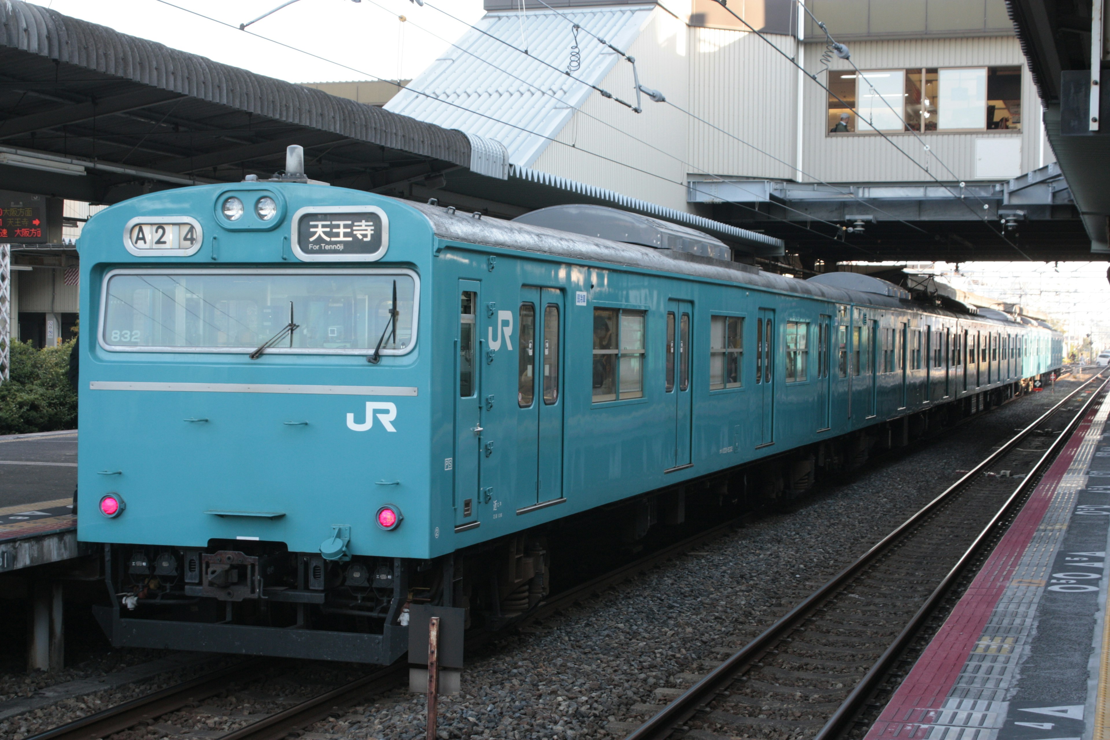 青いJR電車が駅のプラットフォームに停車中