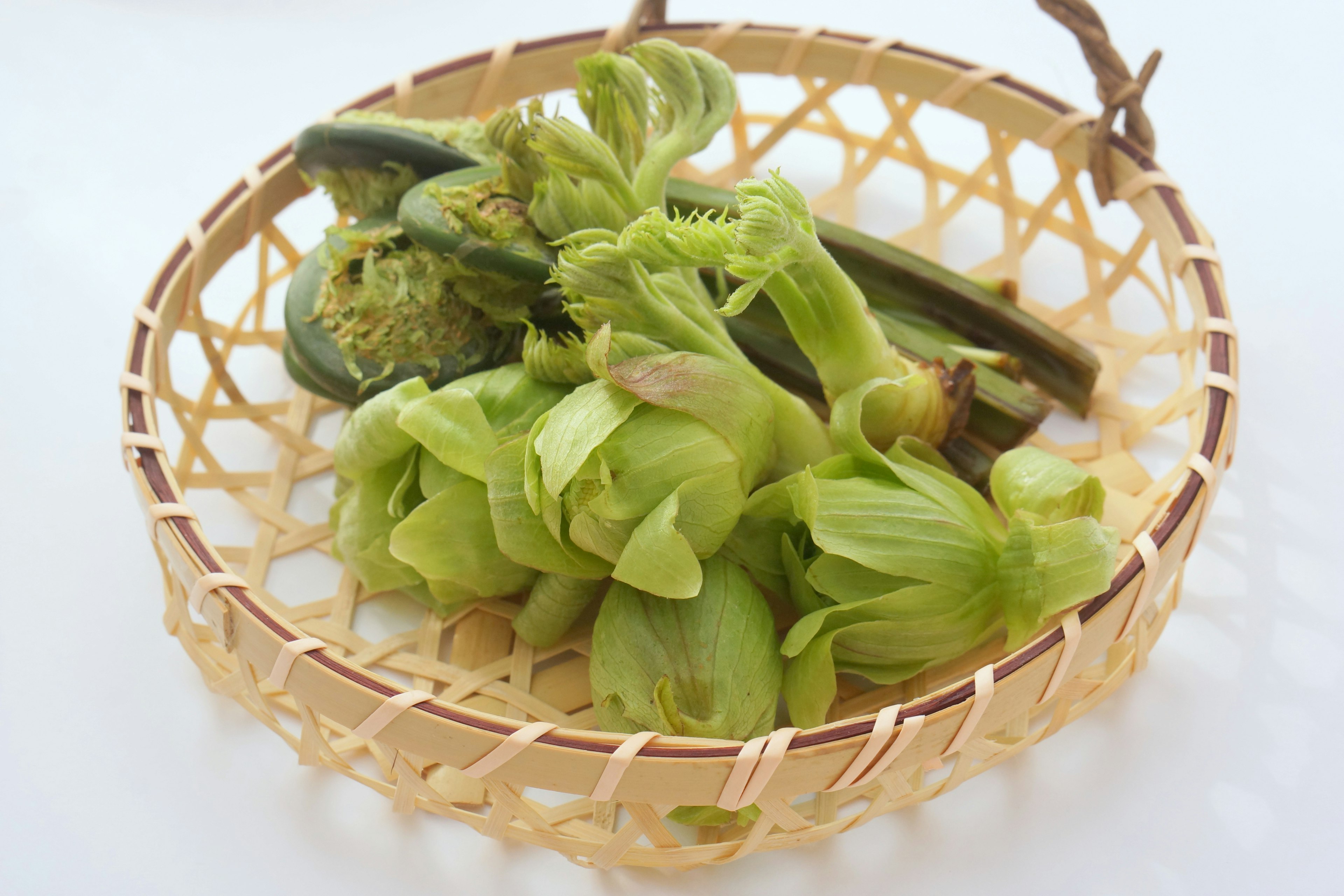 Fresh green vegetables arranged in a bamboo basket