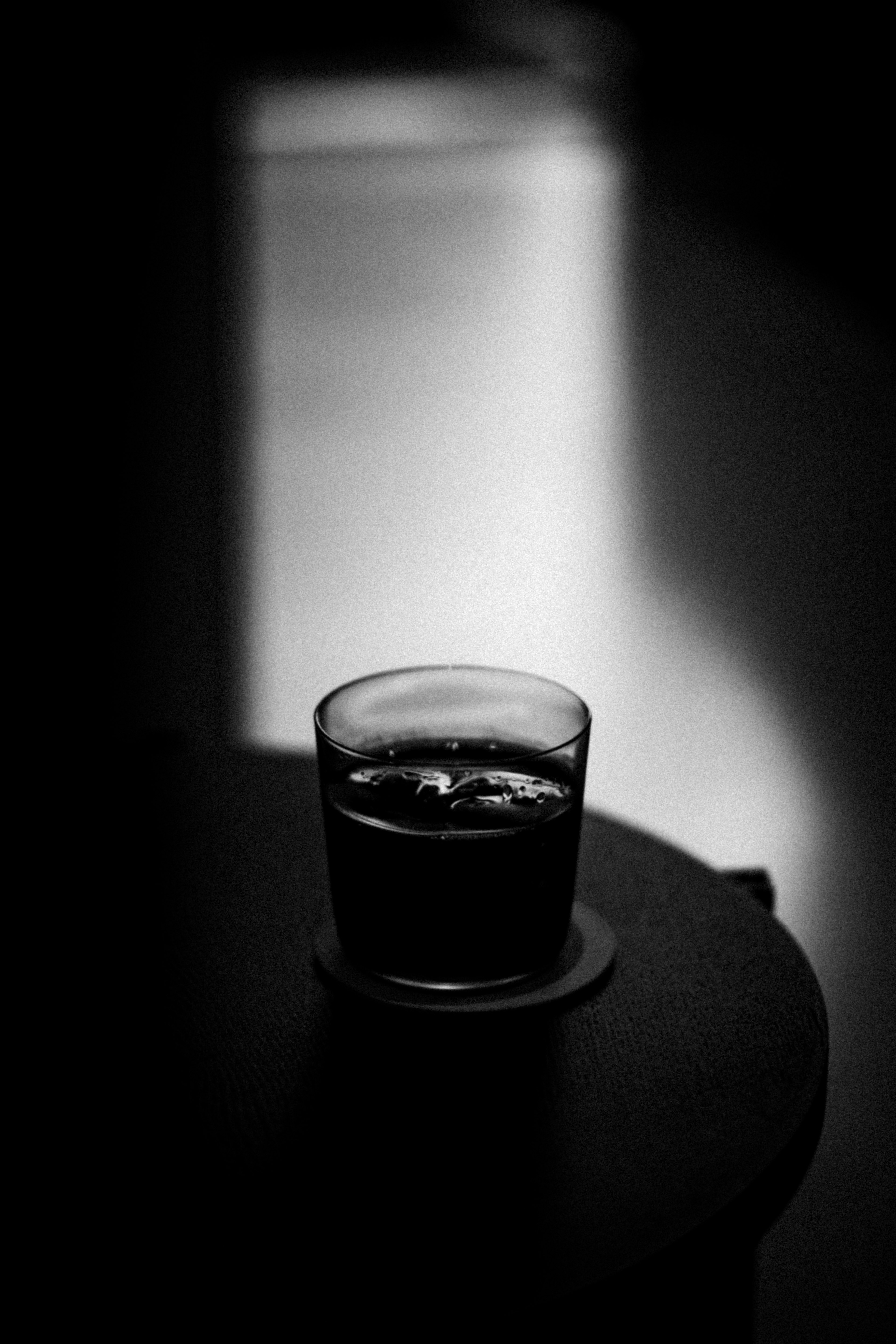 Un verre de boisson avec de la glace posé sur une table dans un contraste noir et blanc