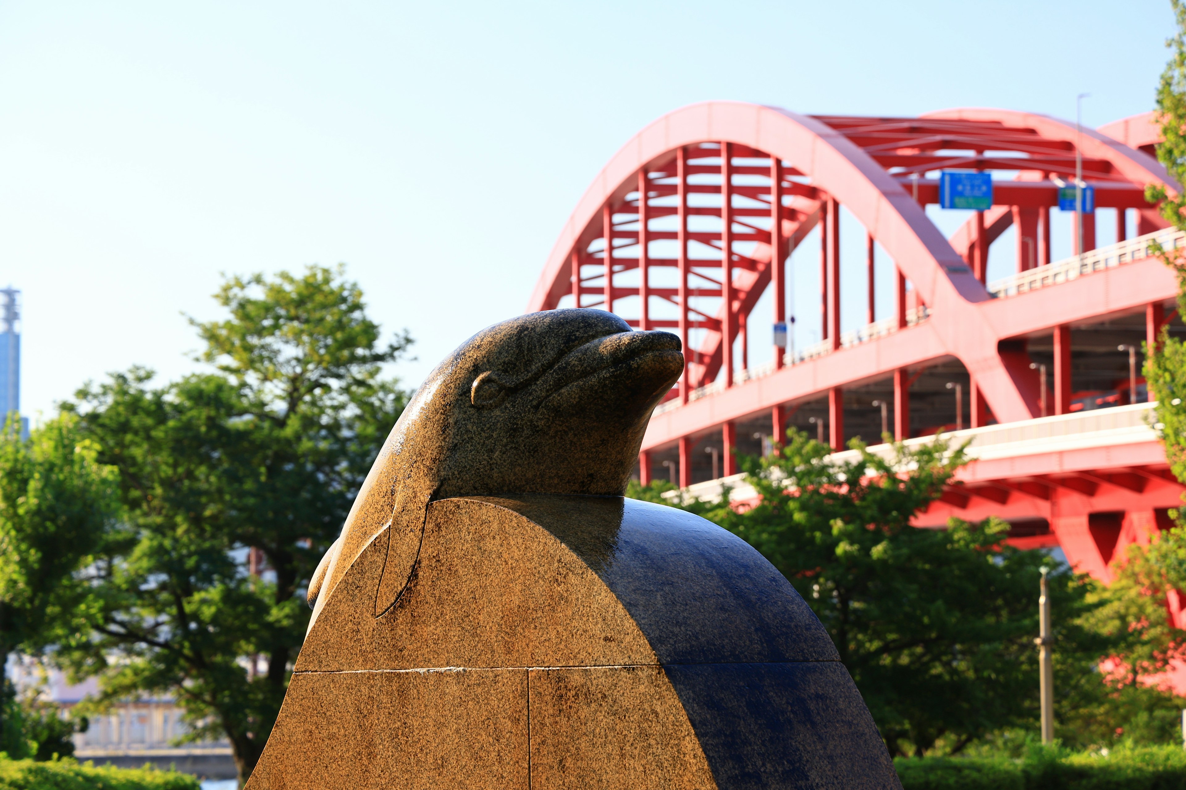 Stone dolphin sculpture near a red bridge