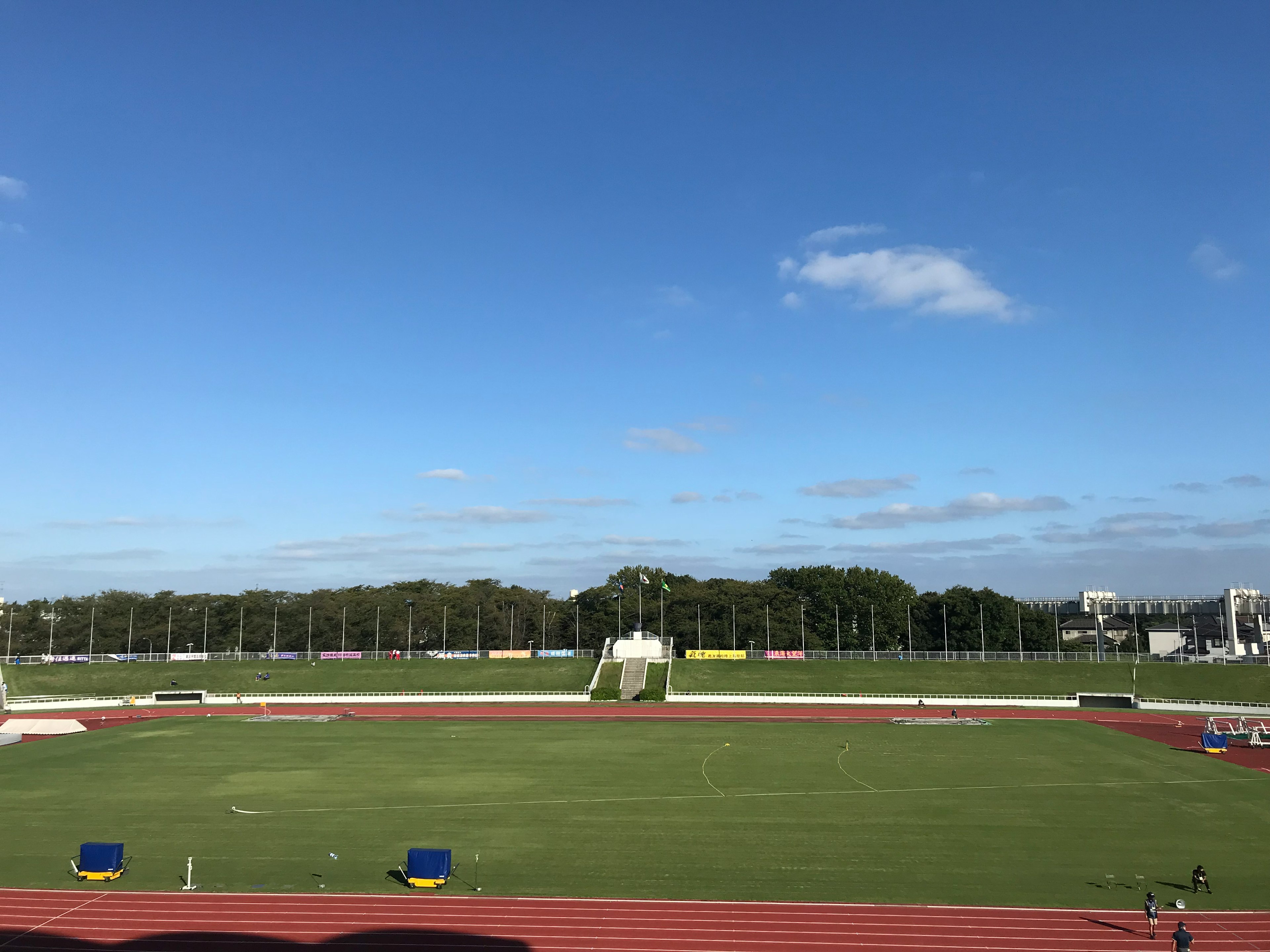 青空と緑の芝生が広がる運動場の風景