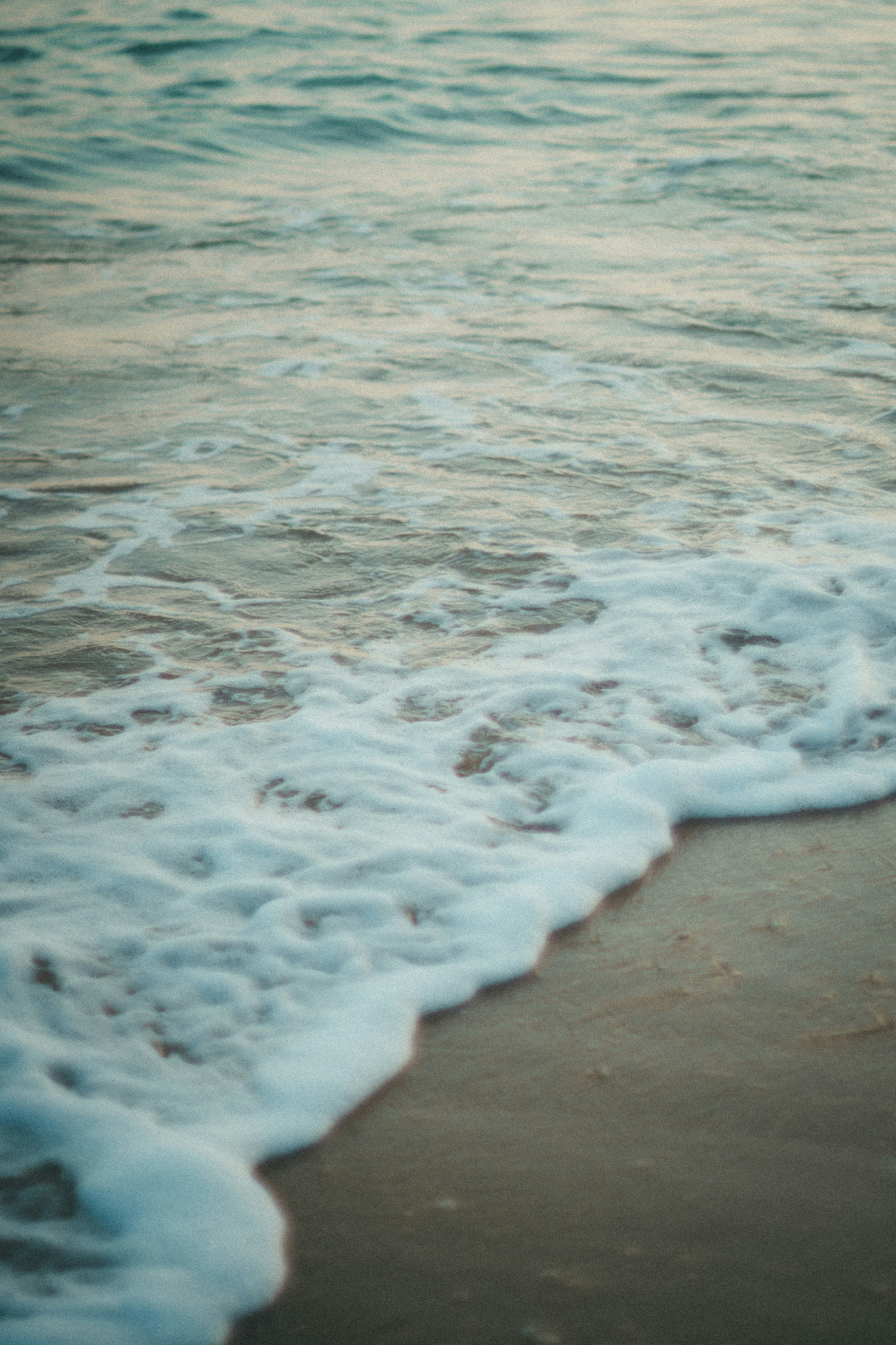 Sanfte Ozeanwellen, die an den Sandstrand schlagen