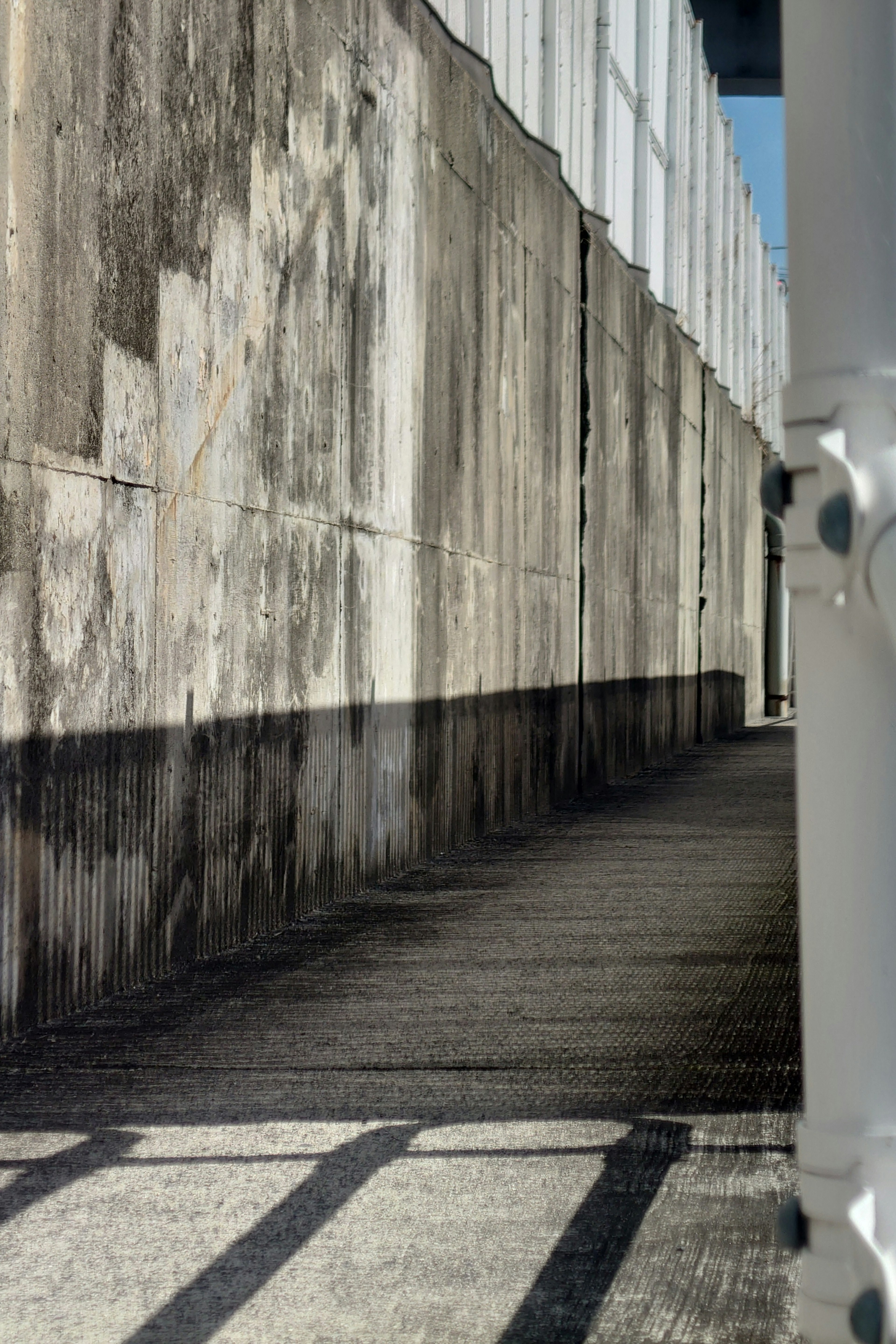 Un camino con sombras proyectadas por una pared antigua