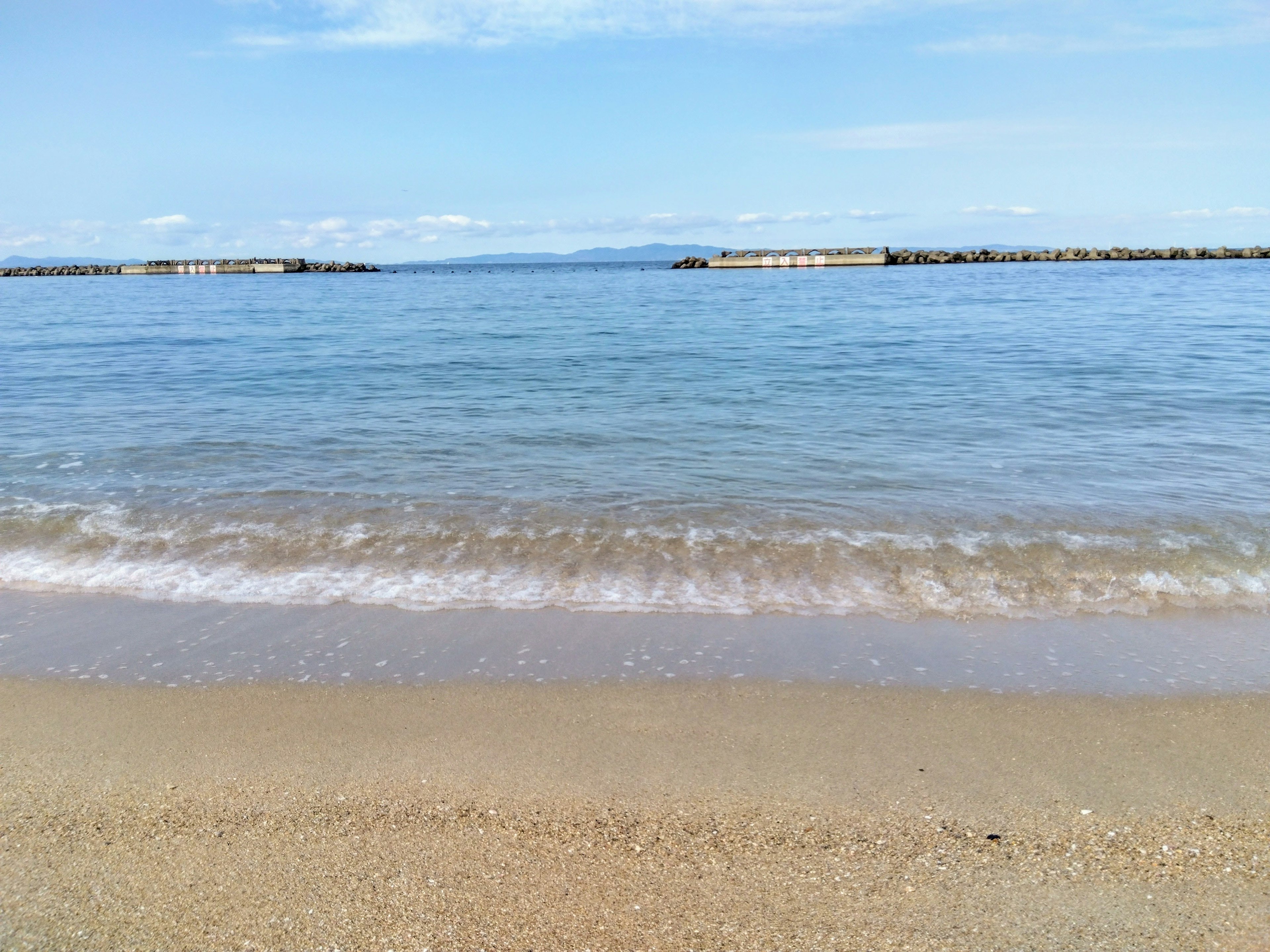 Calm beach scene with blue sky and ocean sandy shore with gentle waves