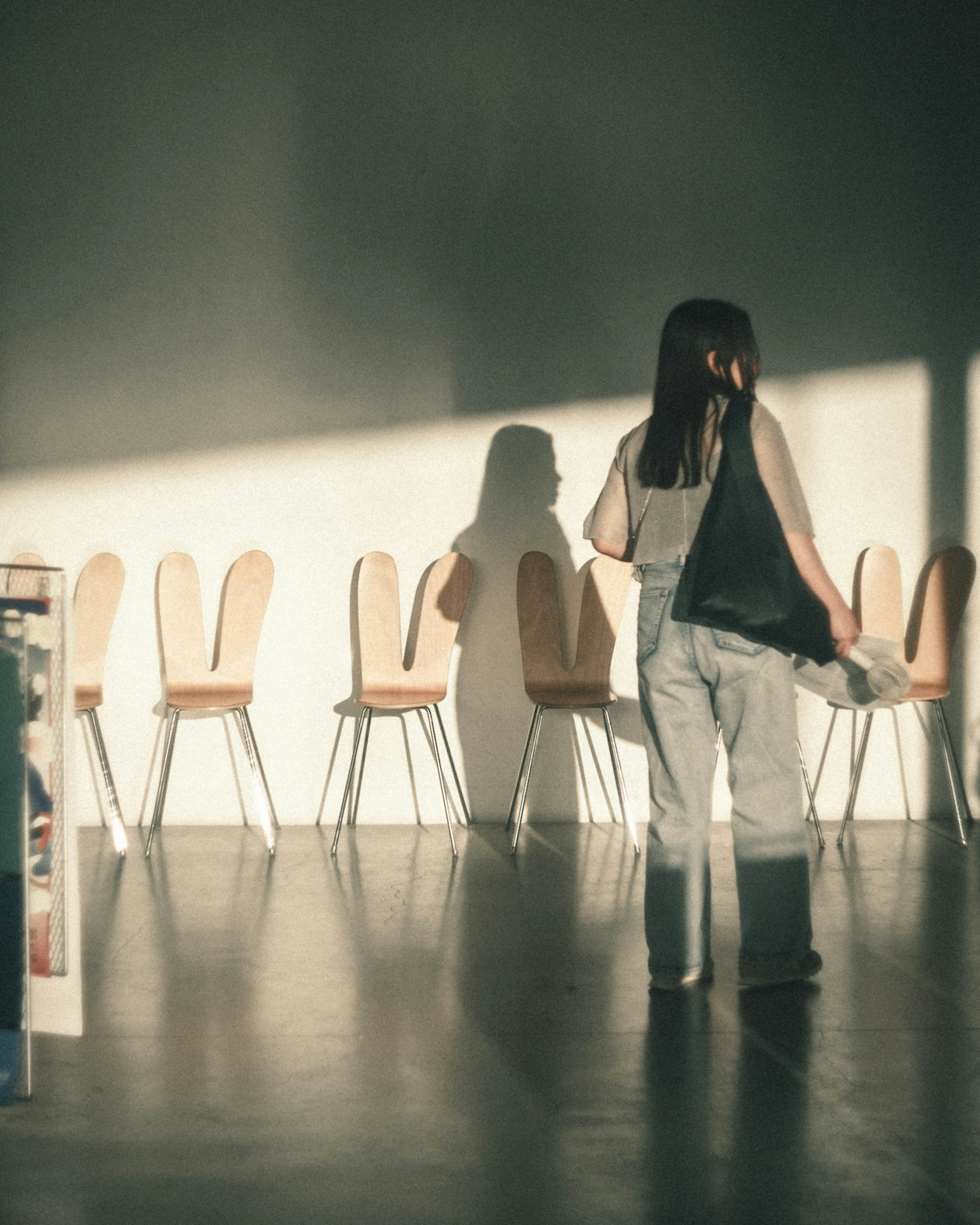 Woman standing in front of chairs casting shadows