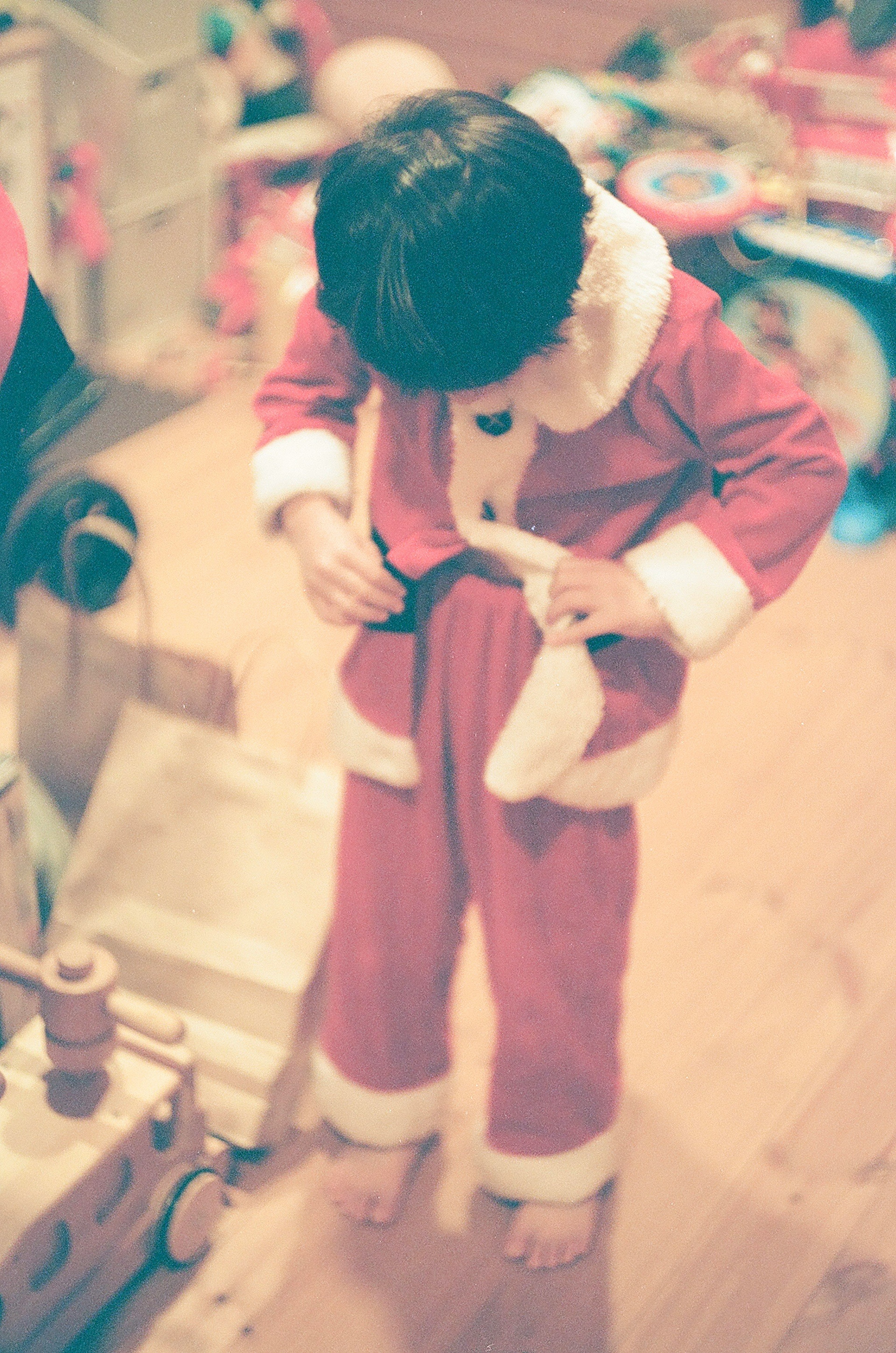 Child adjusting a red Santa costume with white trim