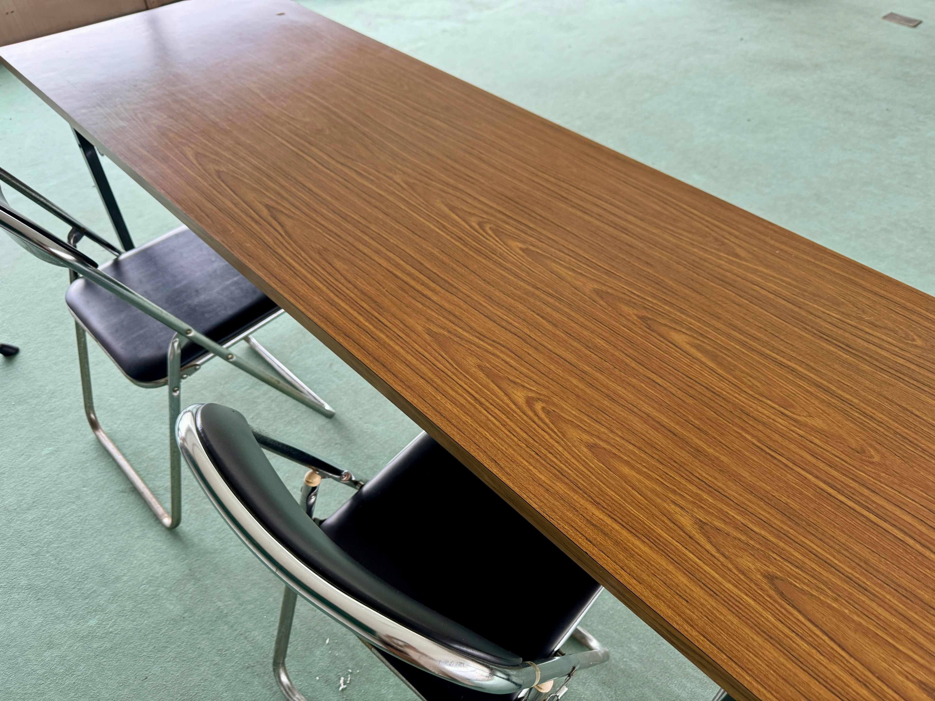 Long wooden table with black chairs in a simple indoor setting