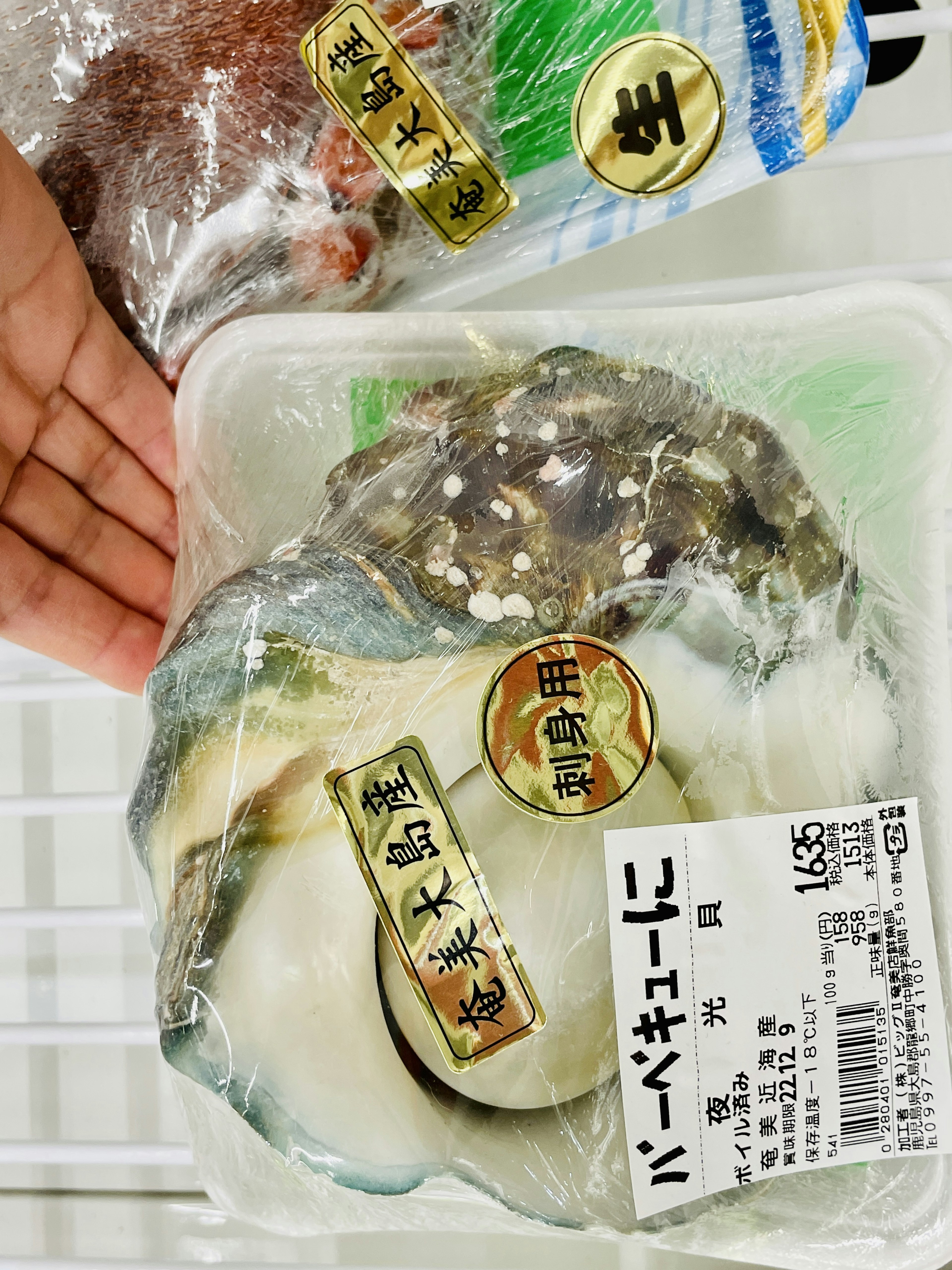 手に持たれた新鮮な貝類のパッケージとラベル