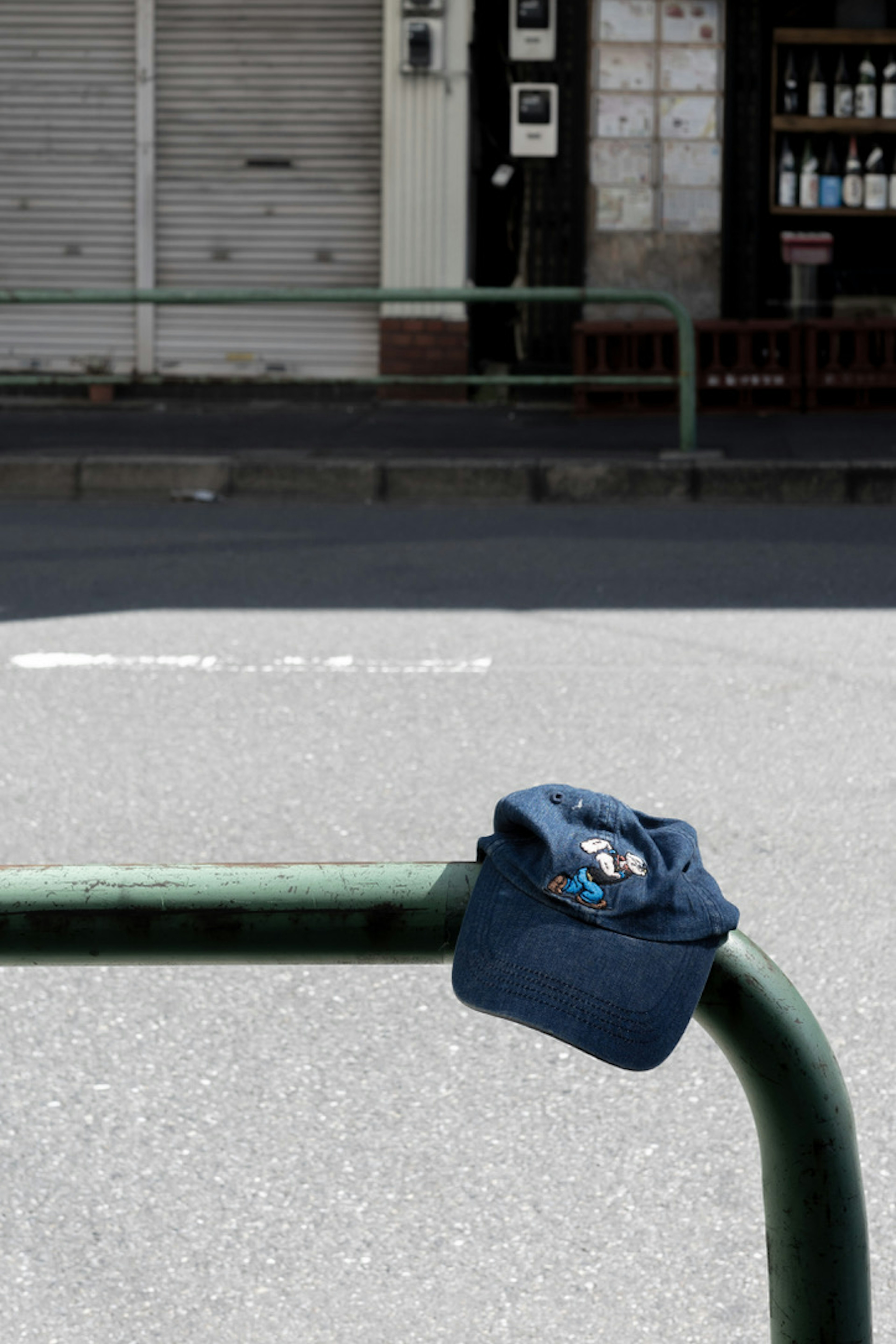 Un cappello blu appoggiato su un corrimano verde in un contesto urbano