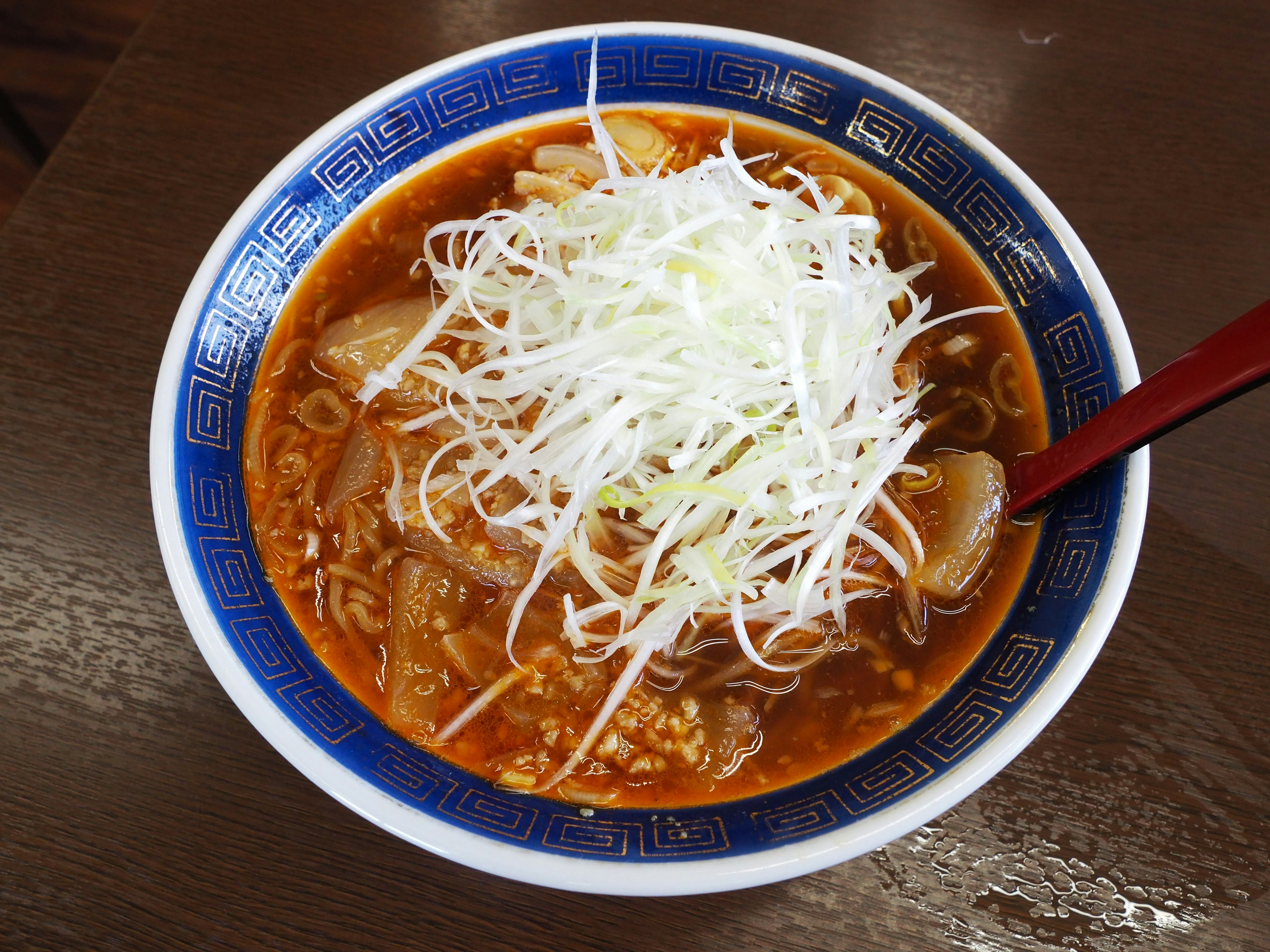 Schüssel mit scharfem Ramen, garniert mit geschnittenen weißen Zwiebeln