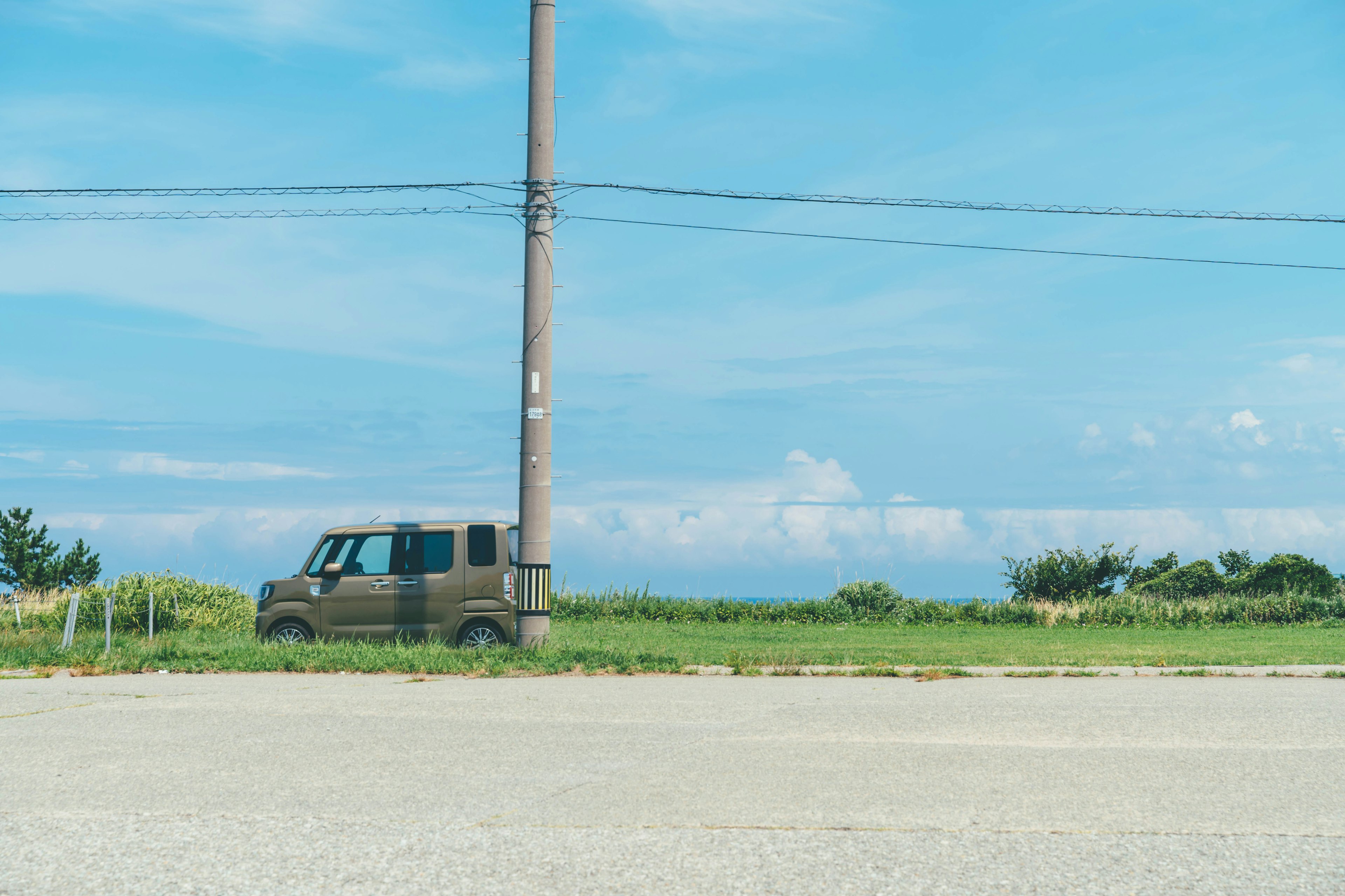 A vehicle parked beside a power pole under a clear blue sky