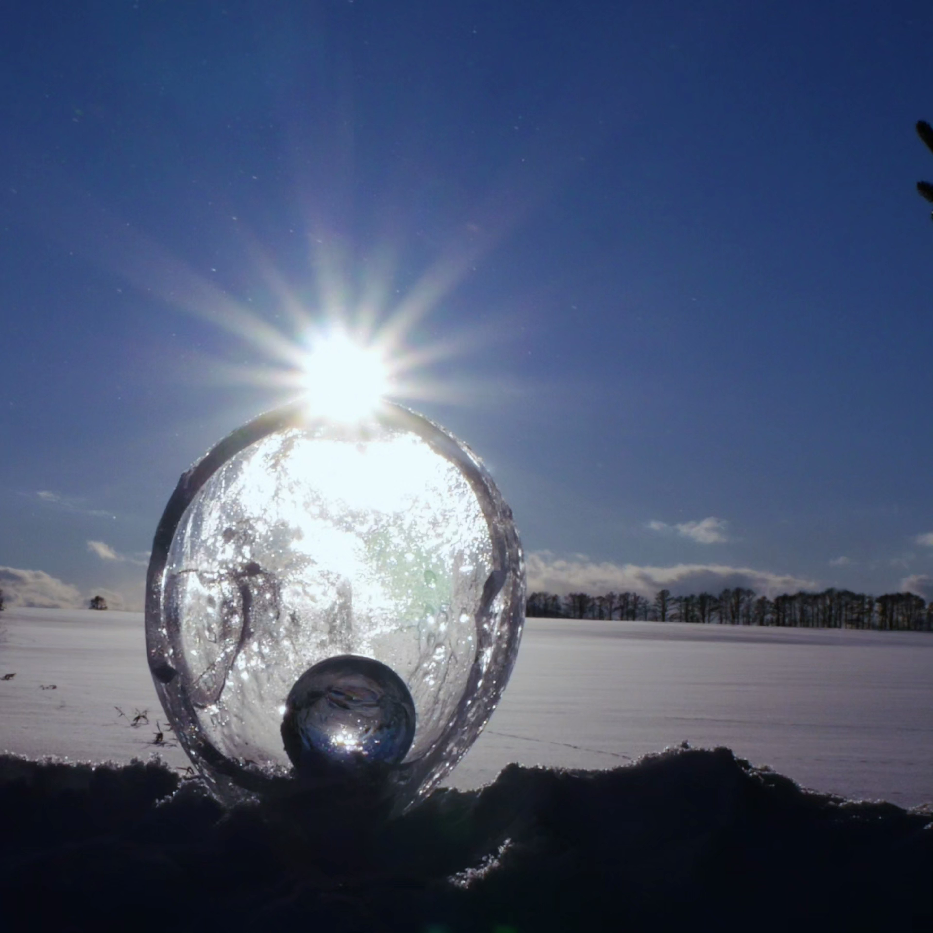 Esfera de hielo brillante con luz solar en un paisaje nevado