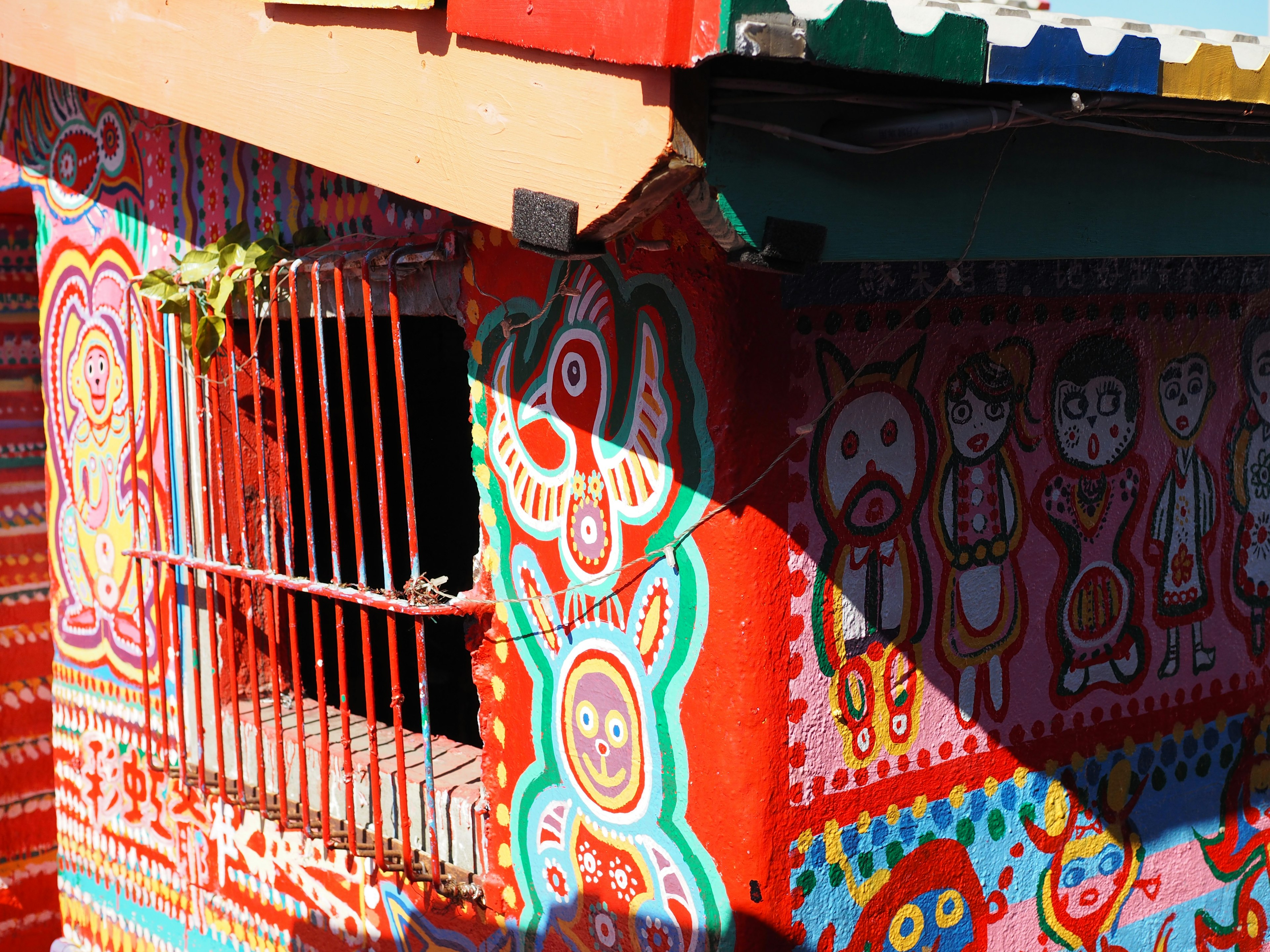 Bâtiment peint coloré avec des motifs vibrants Nuances de rouge et bleu illuminées par la lumière du soleil