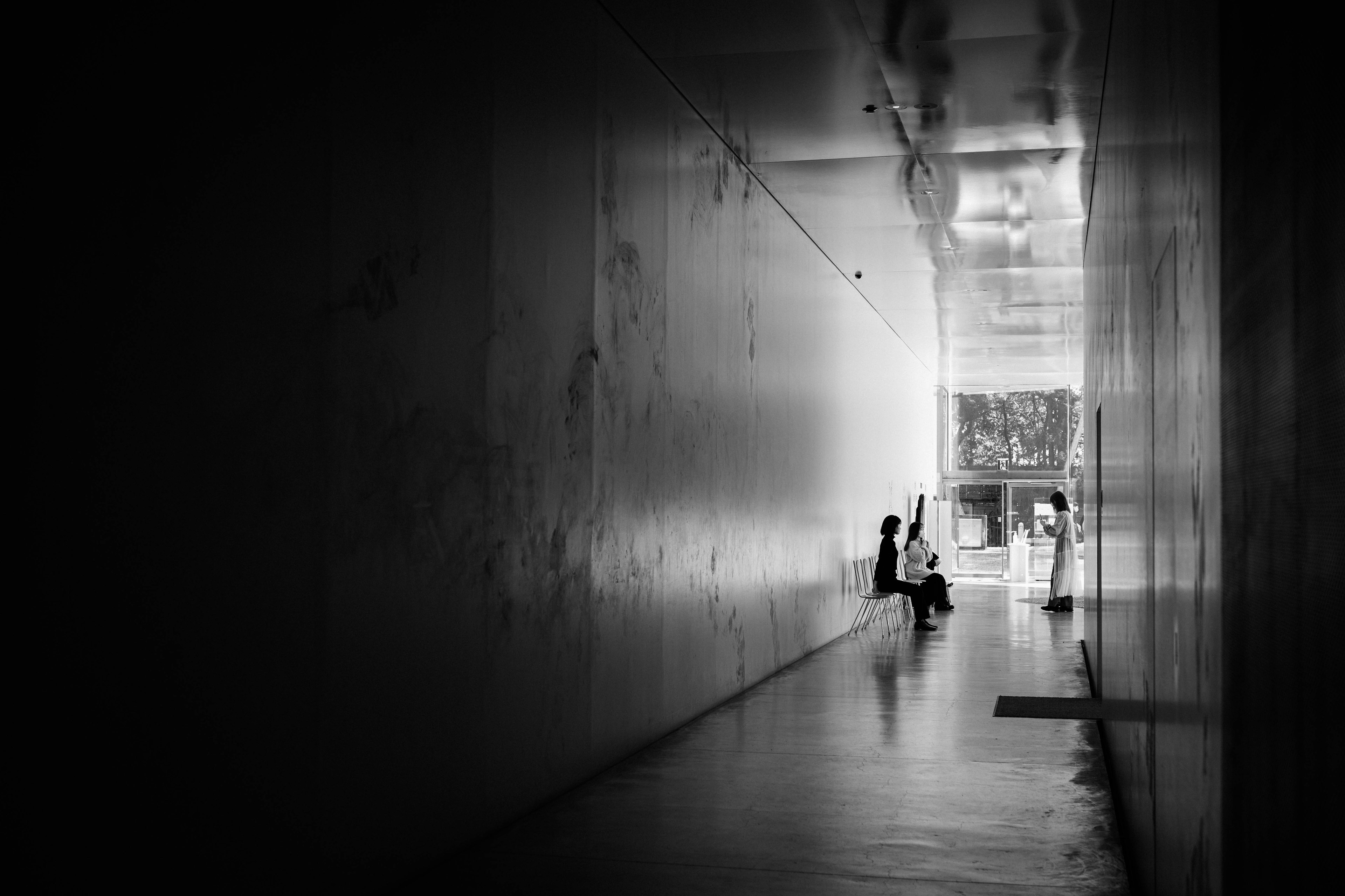 Deux silhouettes dans un couloir sombre avec une sortie lumineuse