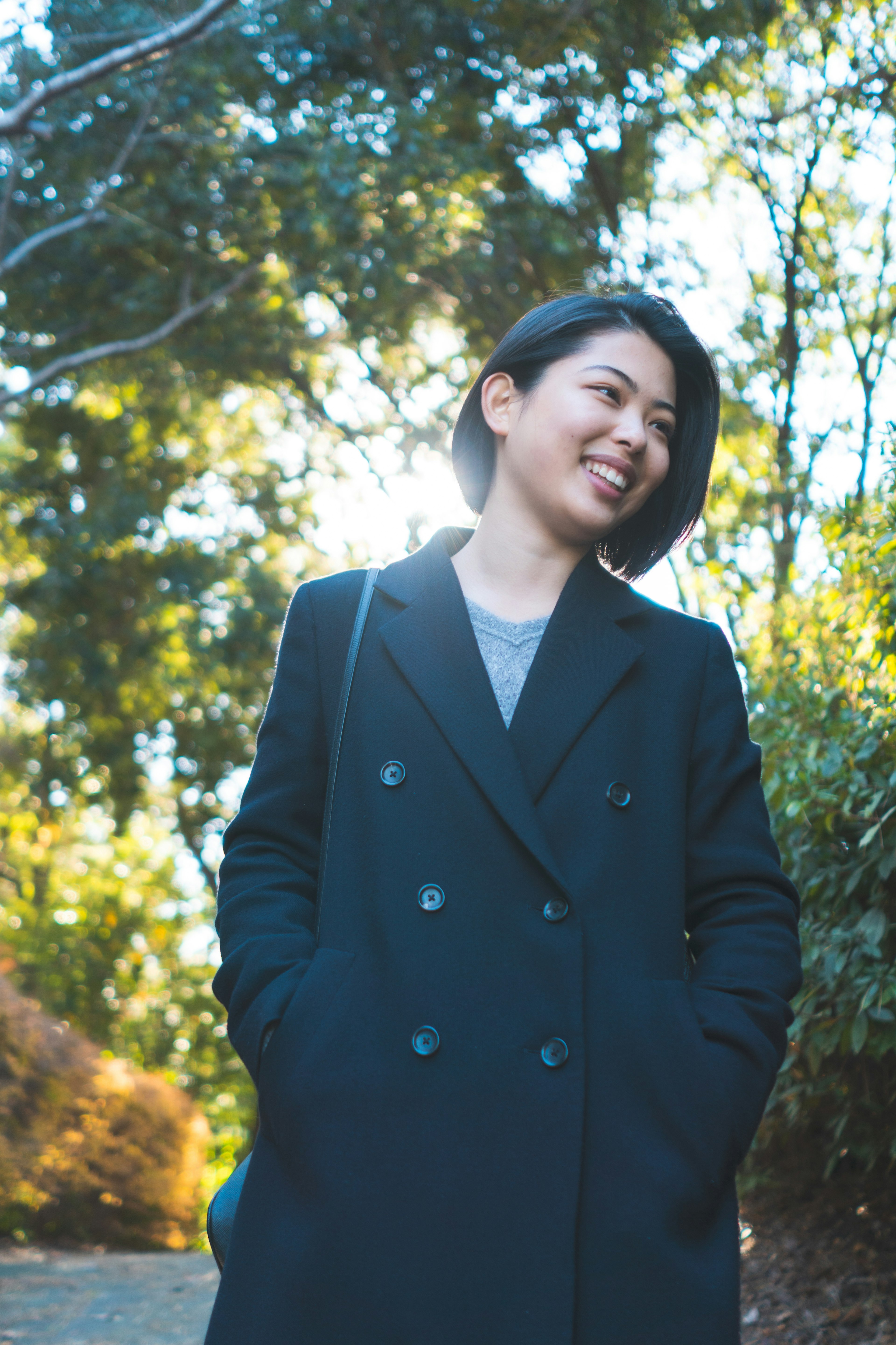 Young woman smiling in a green background wearing a black coat