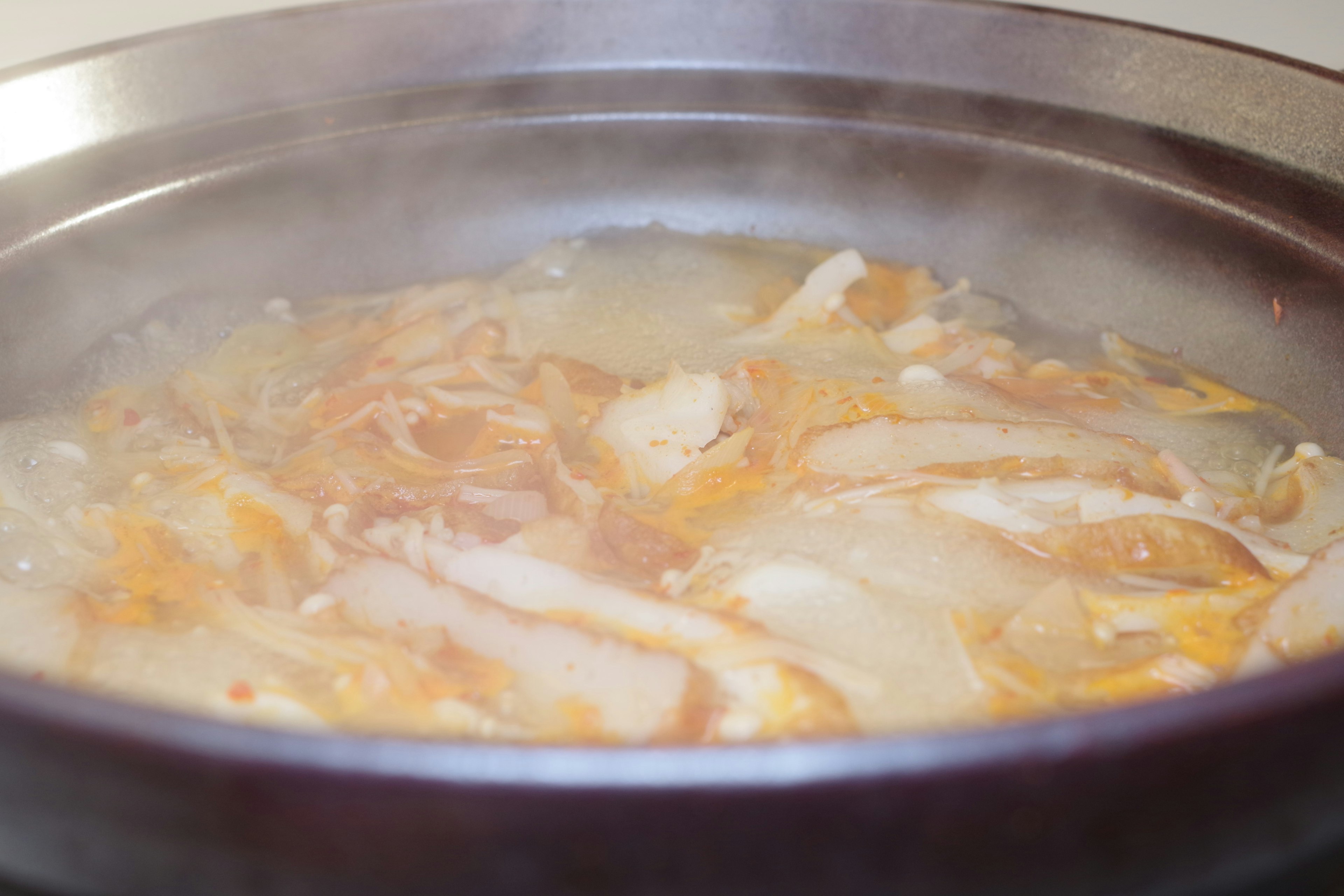 蒸気が立ち上る鍋の中で煮込まれた鶏肉と野菜の料理