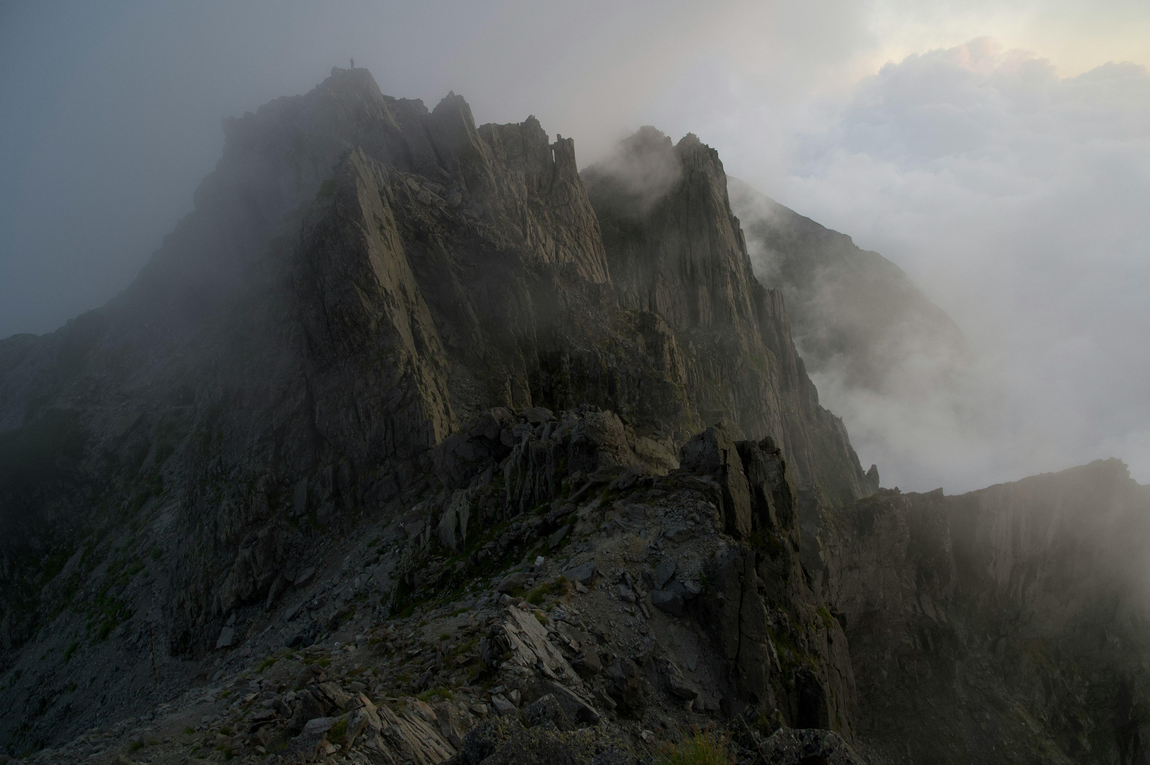 Pics de montagne en dents de scie enveloppés de brouillard et de nuages