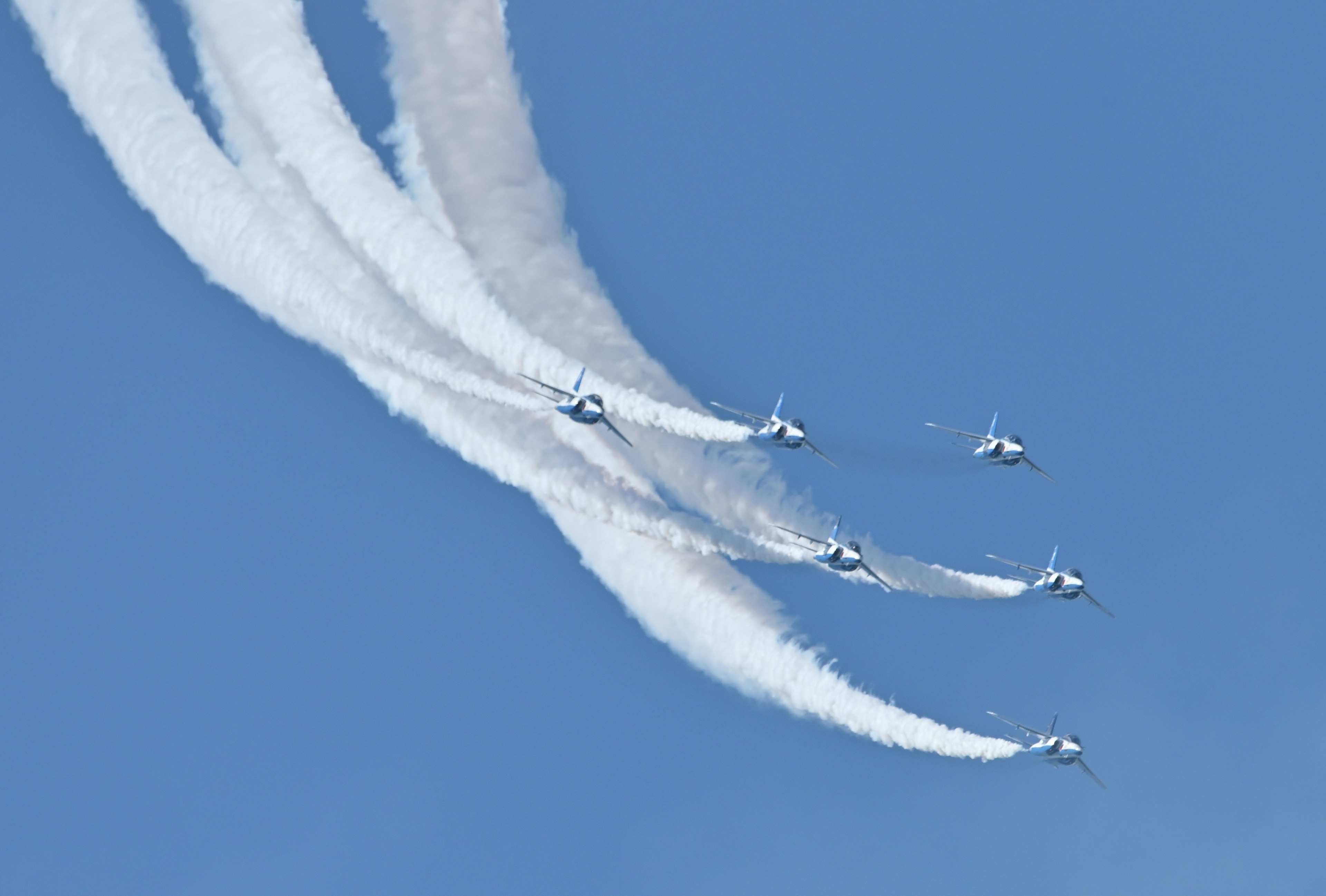 Formation flight of fighter jets leaving smoke trails in the blue sky