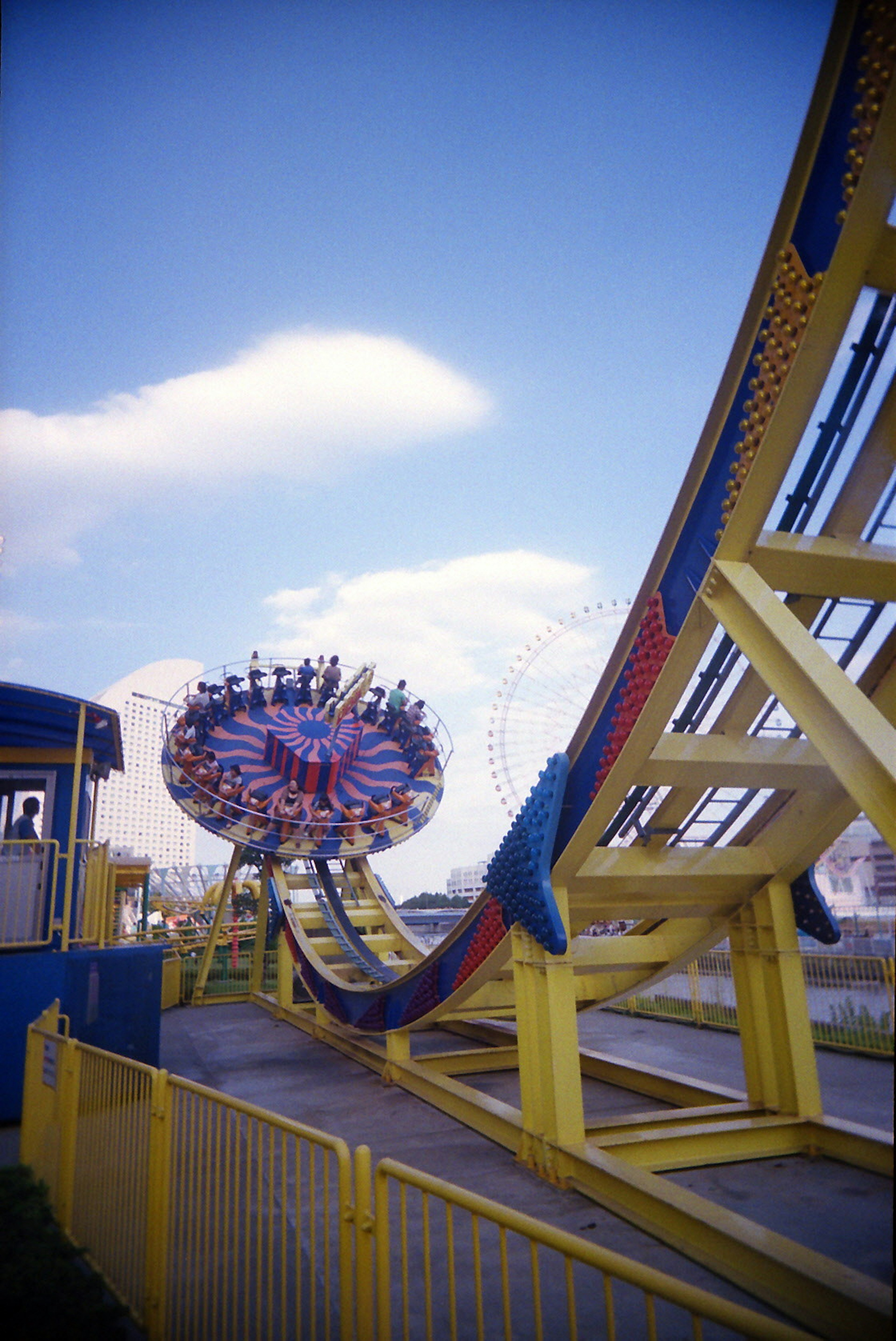 Farbige Abbildung einer Fahrgeschäfte im Freizeitpark mit einer hohen Bahn und einer drehenden Attraktion