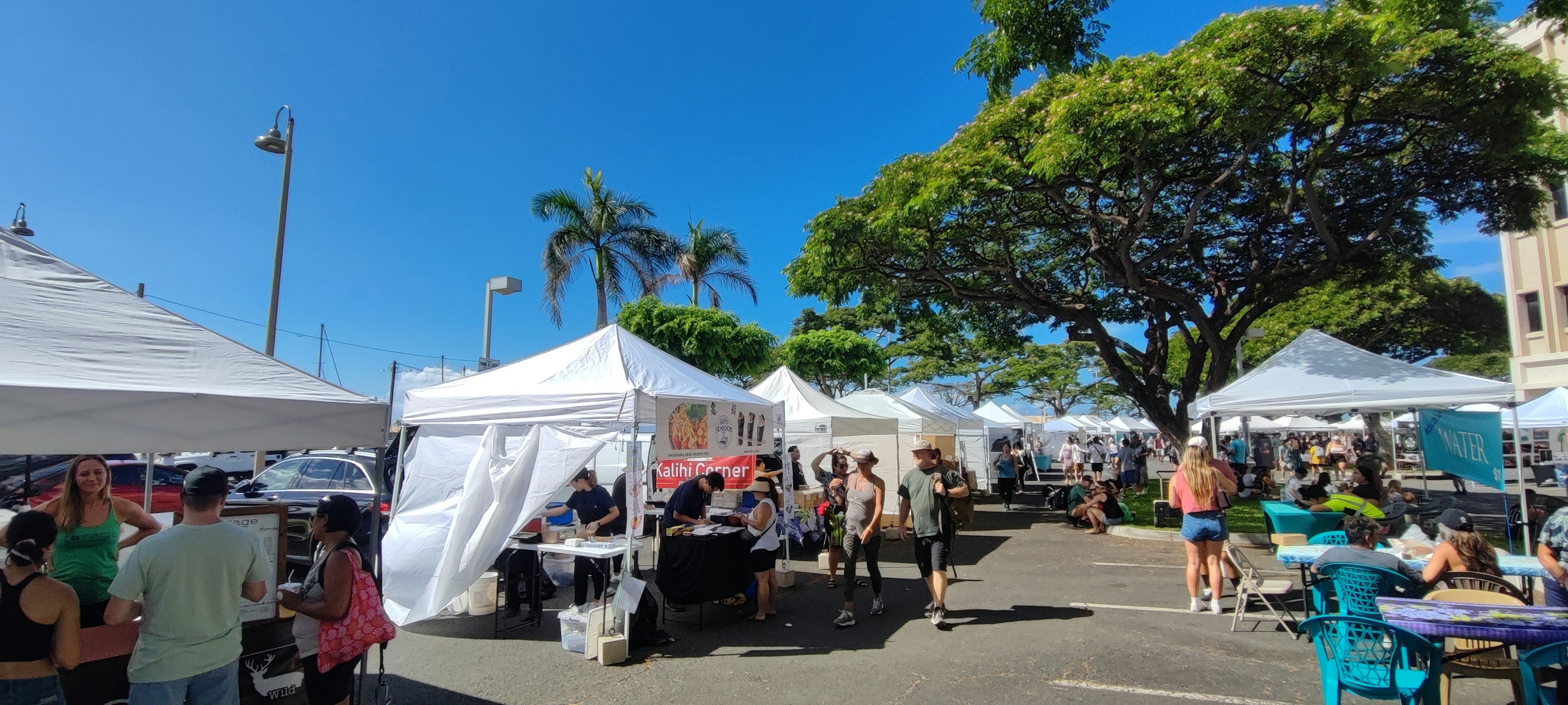 Escena de mercado con carpas blancas bajo un cielo azul claro