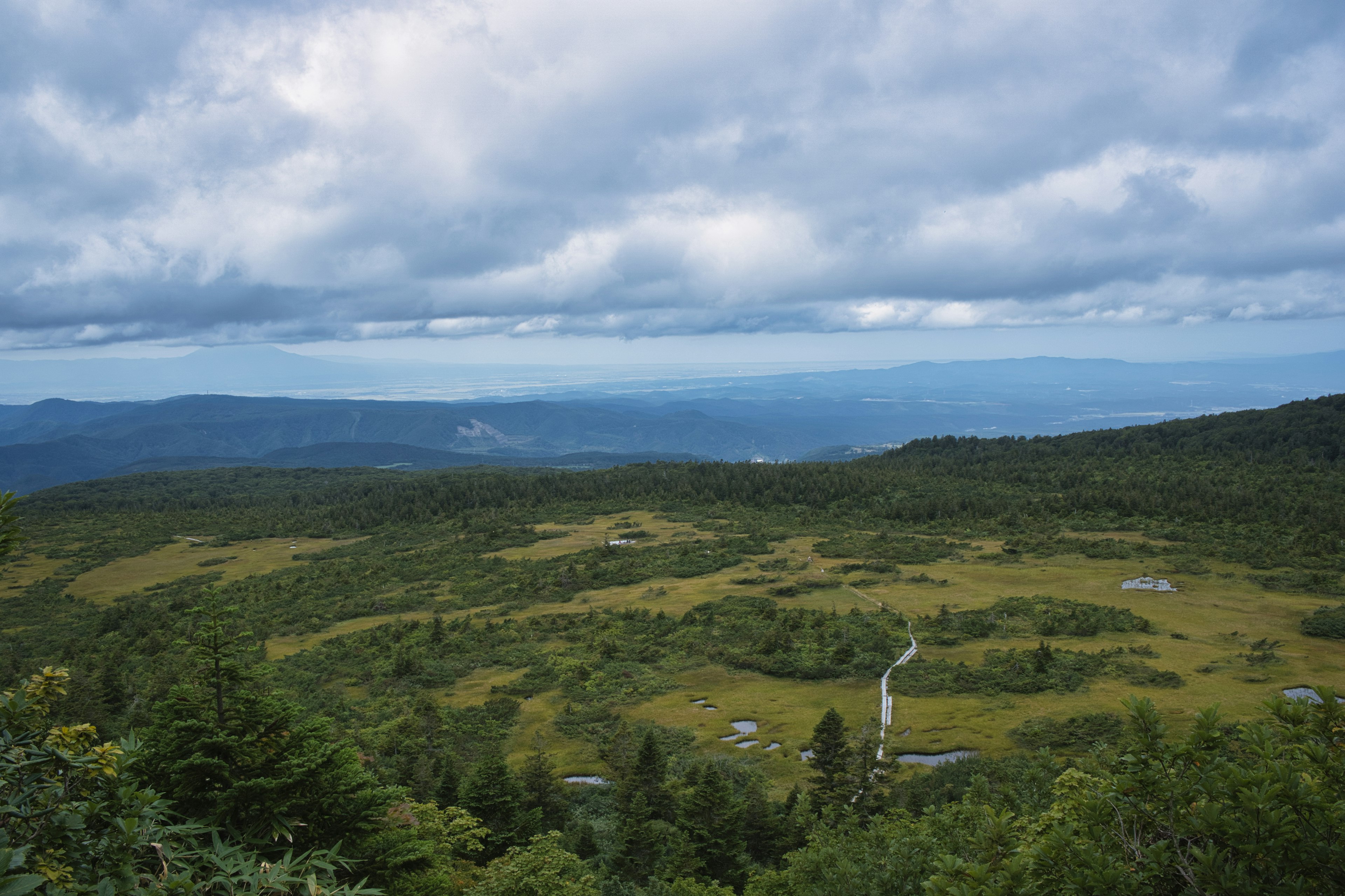 Amplio paisaje montañoso con praderas verdes y cielo nublado