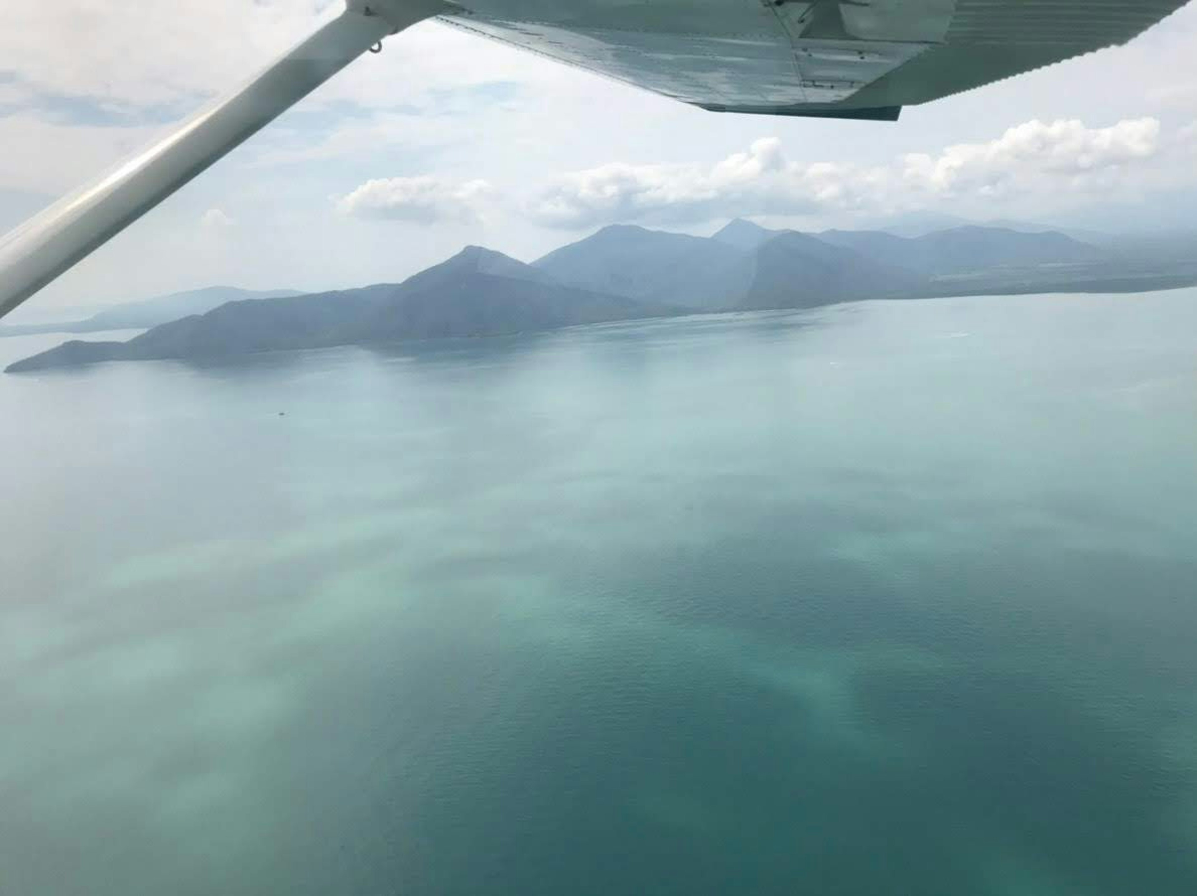 Pemandangan udara di atas perairan tenang dengan gunung di kejauhan