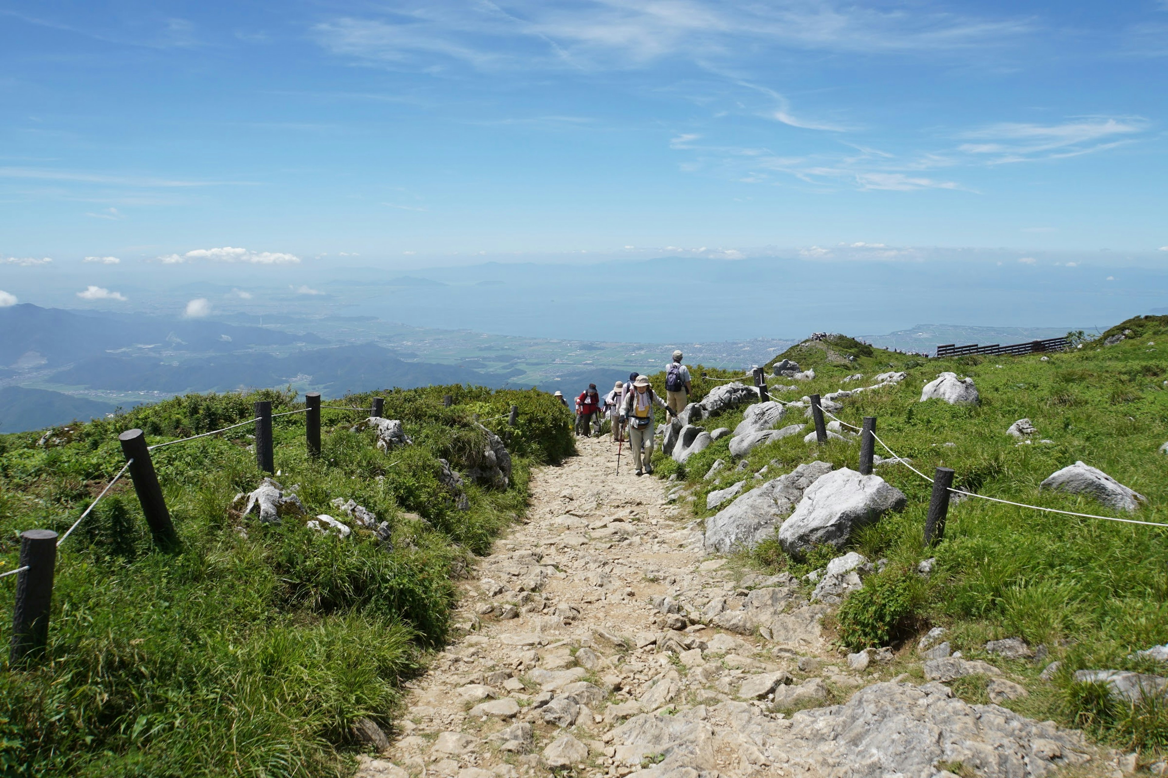 Jalan berbatu menuju puncak gunung dengan rumput hijau