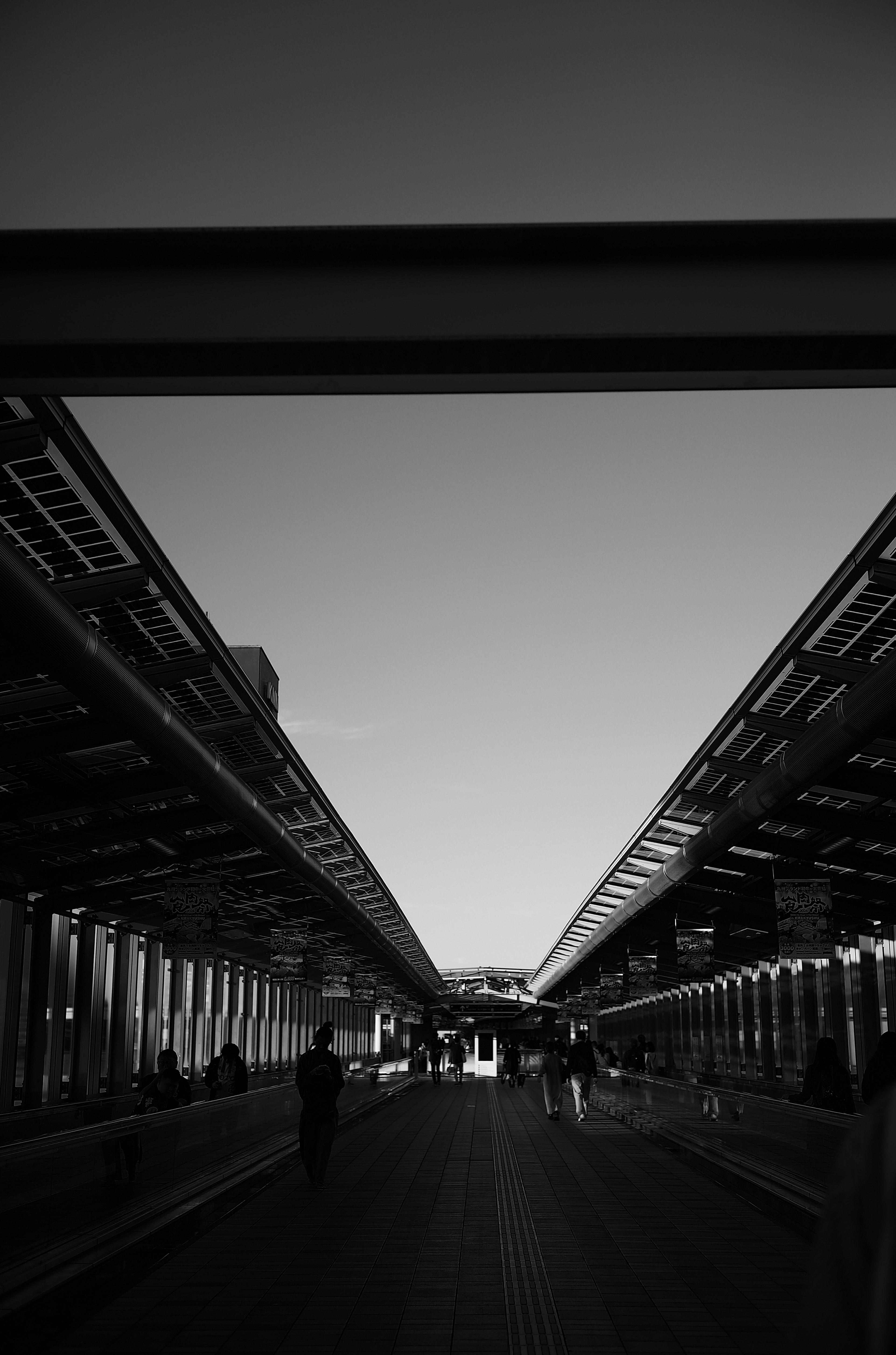 Perspective en noir et blanc d'un chemin sous un pont avec des gens