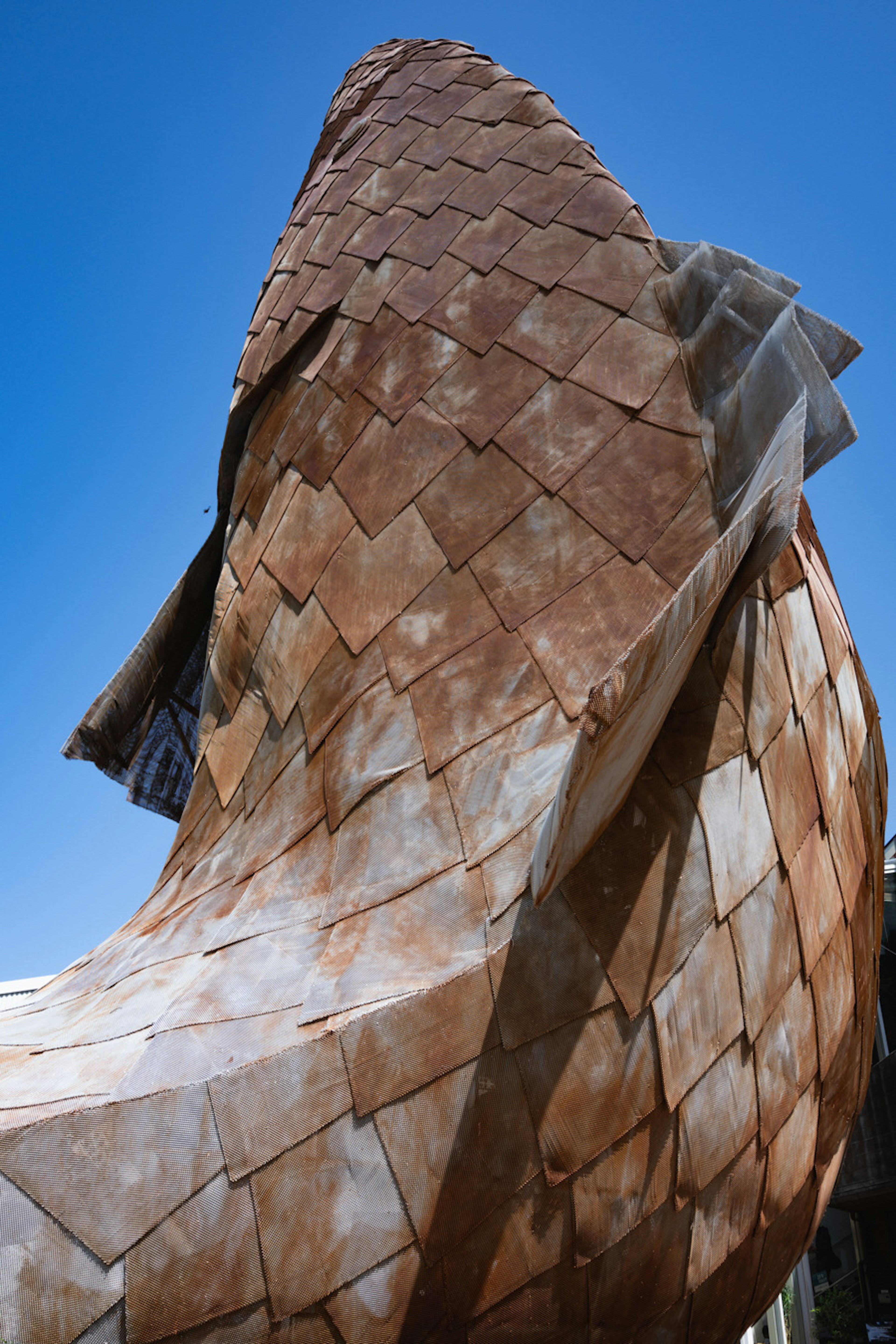 Cette image présente une structure architecturale unique sous un ciel bleu Son apparence métallique usée et sa forme ondulée sont remarquables