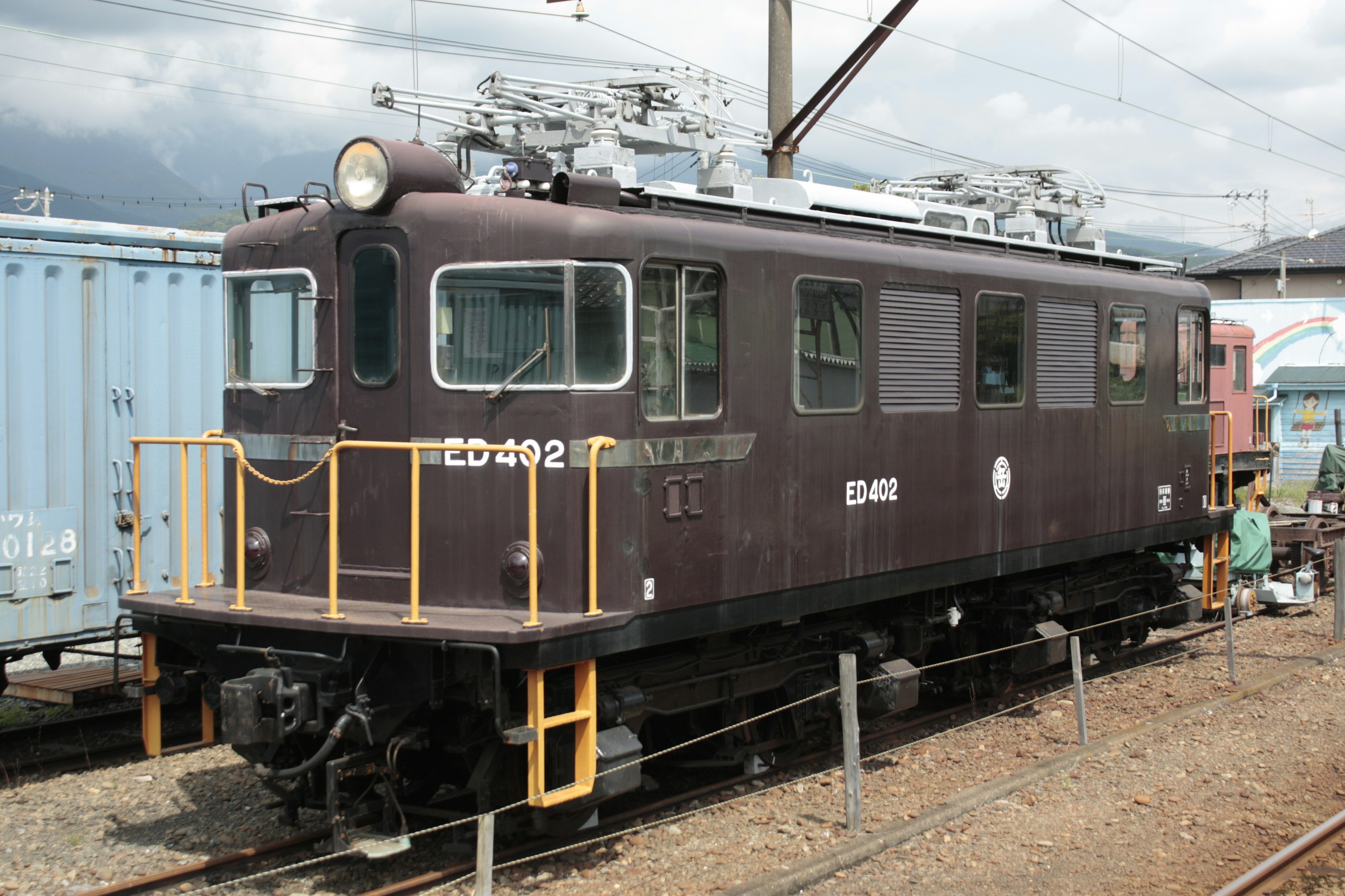 Locomotive électrique brune ED102 garée à une gare