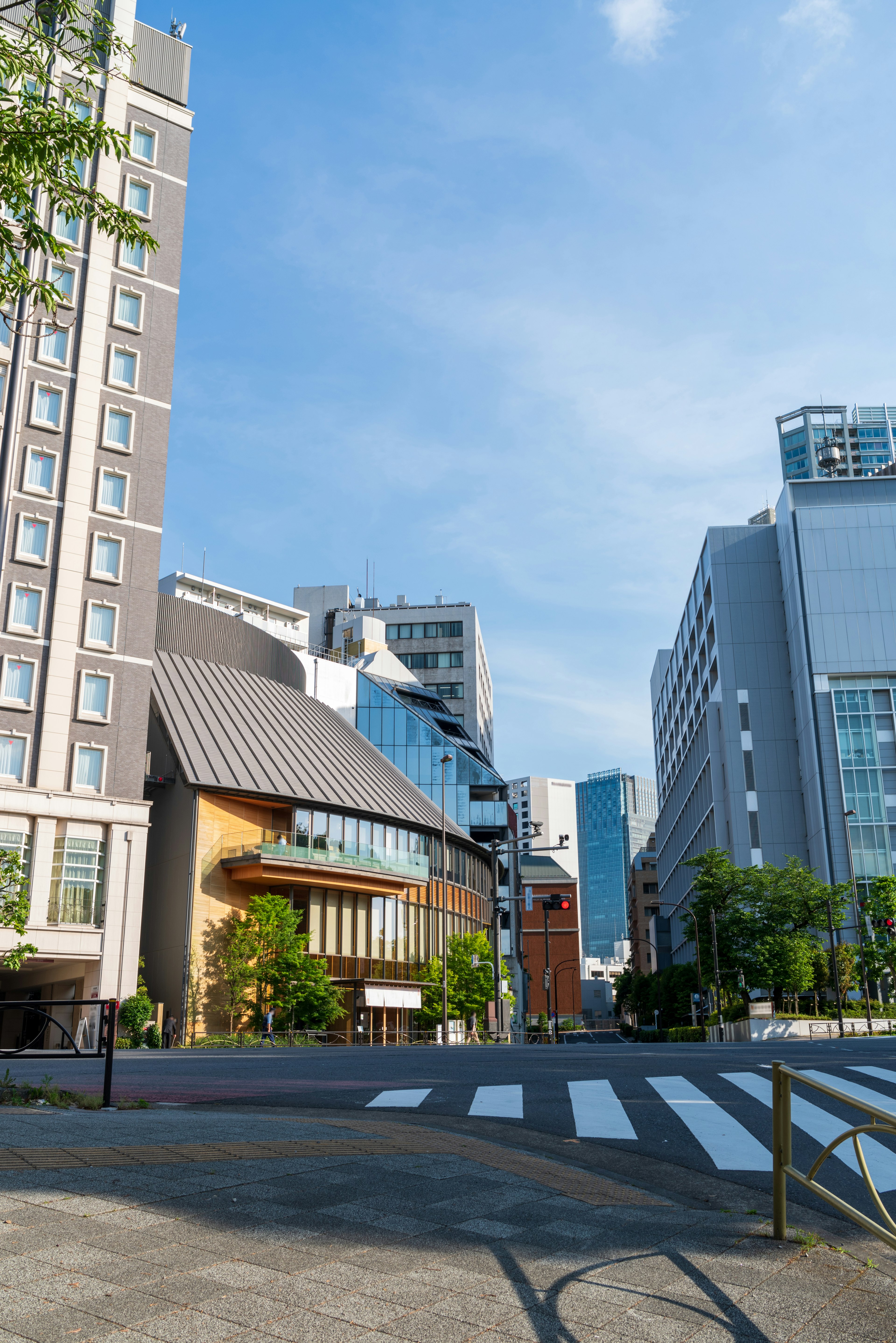 Urban landscape under blue sky featuring high-rise buildings and modern architecture with visible road and crosswalk