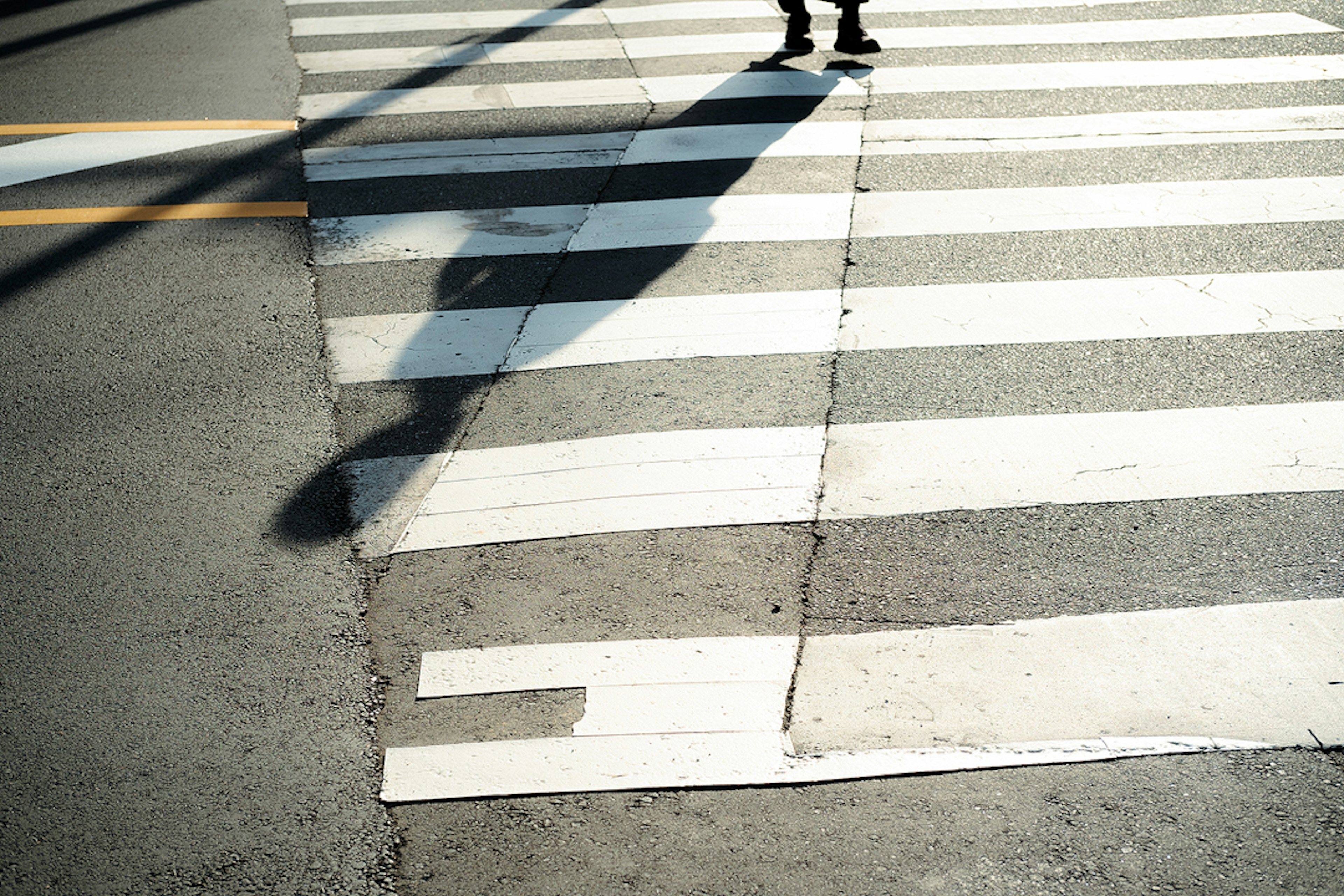 Crosswalk with white stripes and a person's shadow