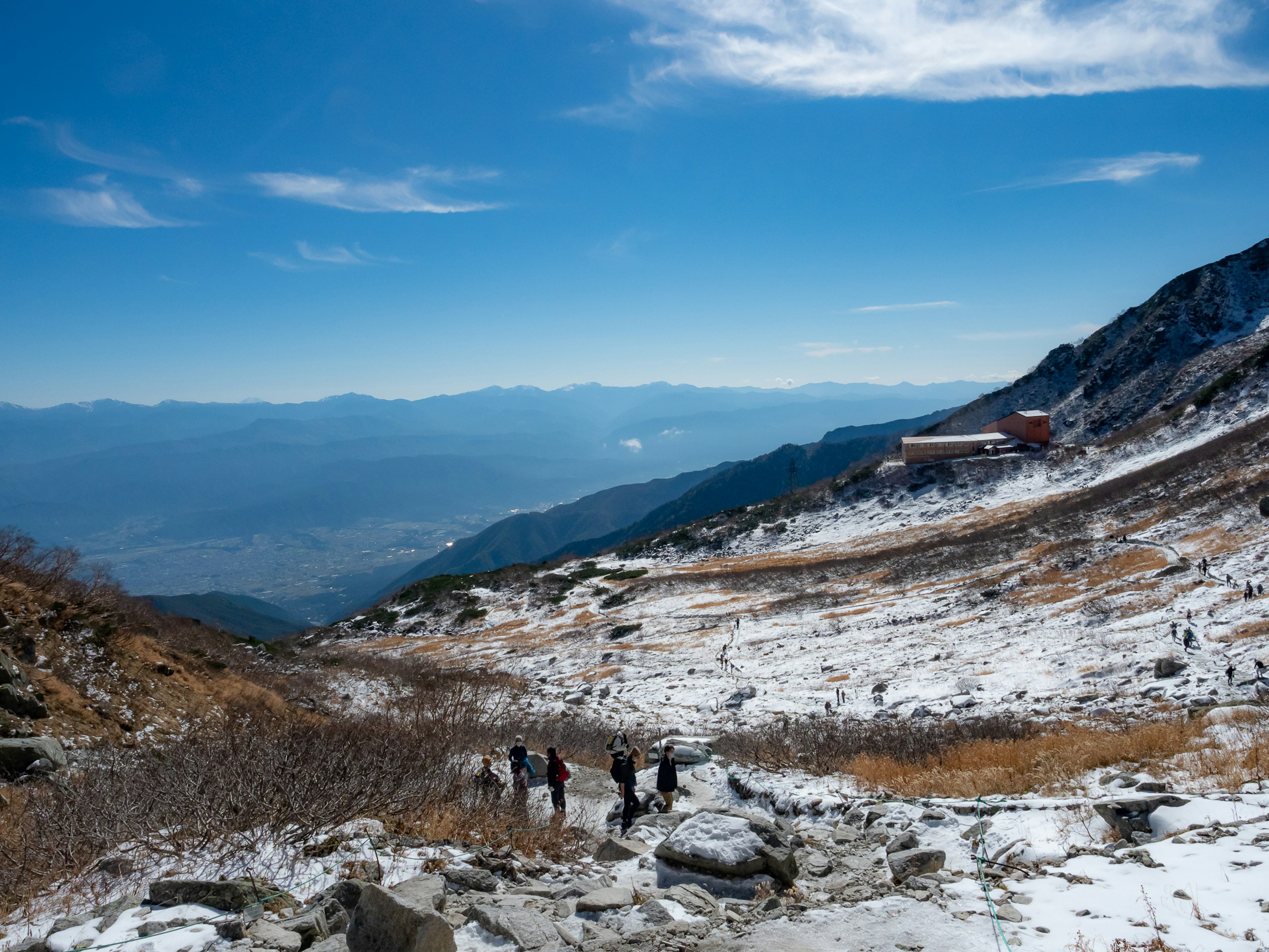 在晴朗藍天下行走的雪山斜坡上的徒步旅行者