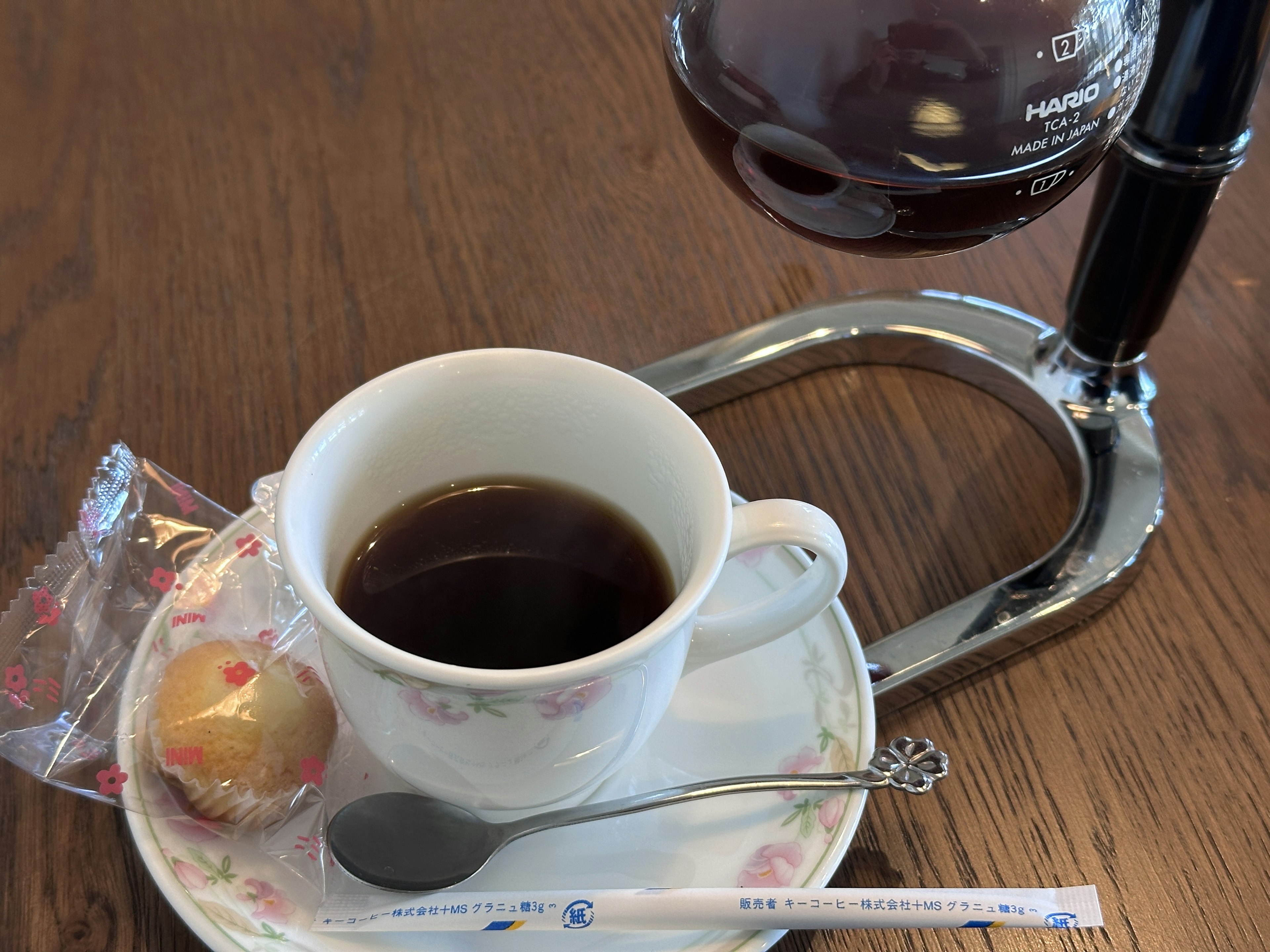 Une tasse de café avec un petit bonbon sur une assiette sur une table en bois