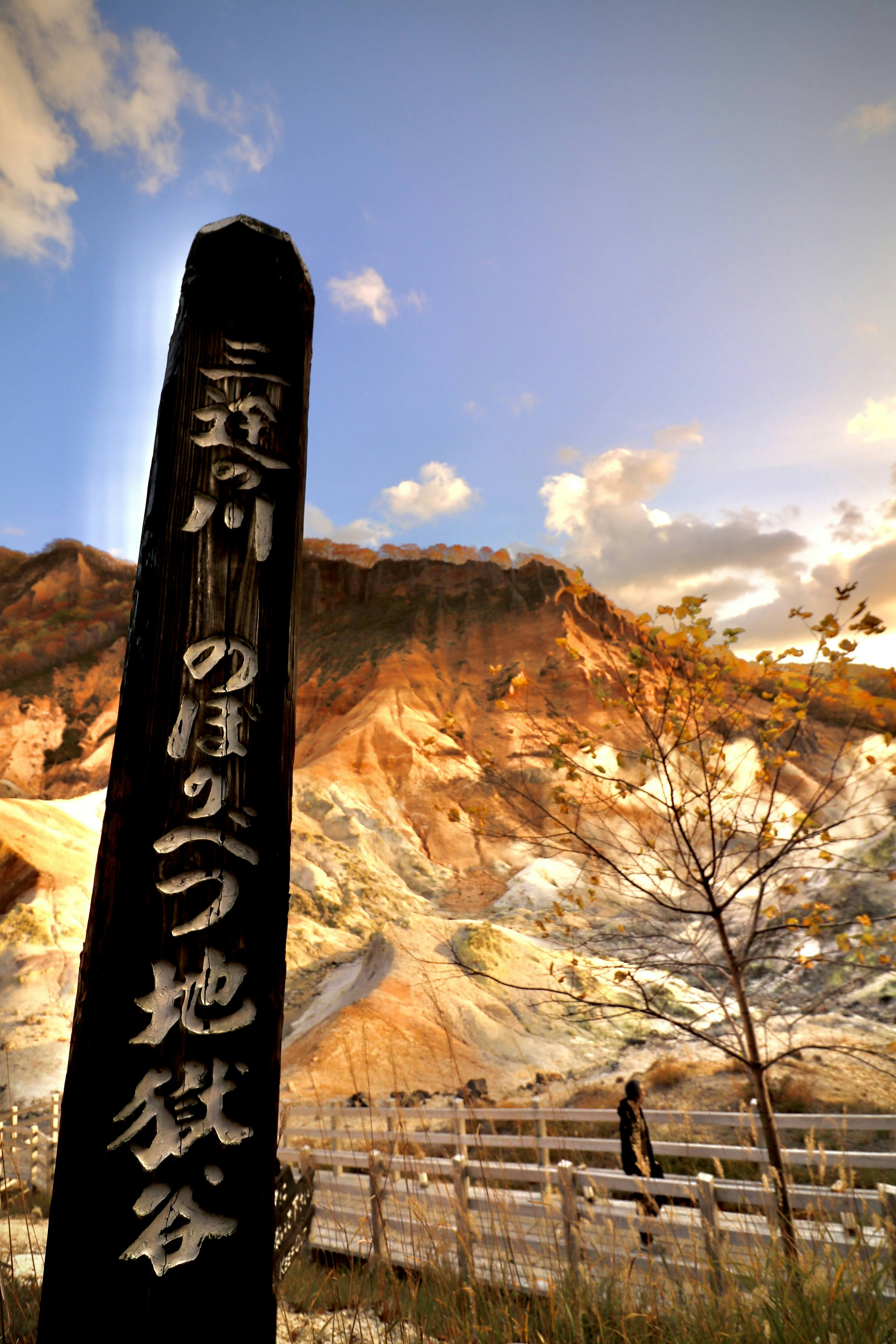 Black signpost in front of colorful mountains and blue sky