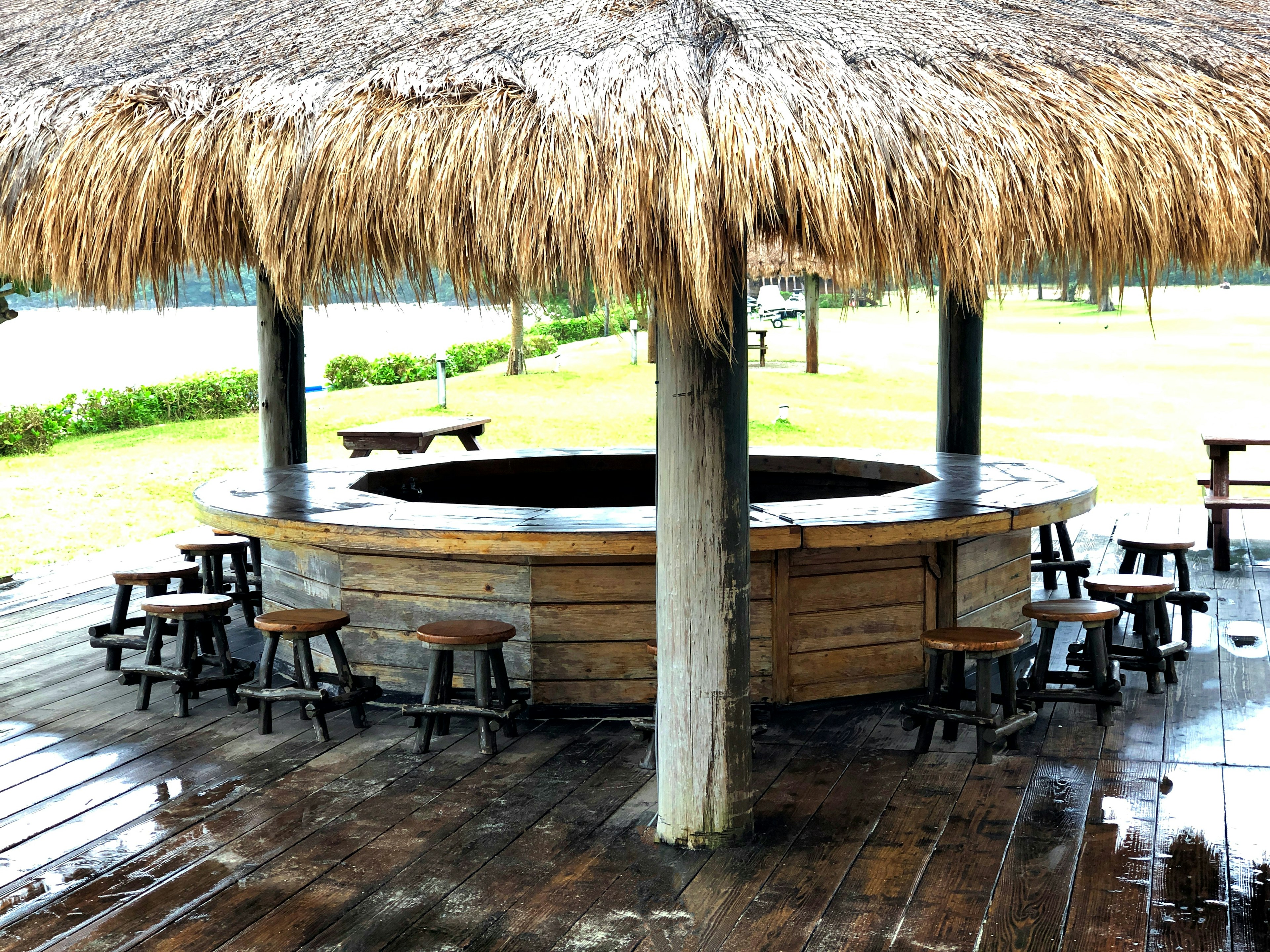 Outdoor pavilion with a wooden circular bar and thatched roof