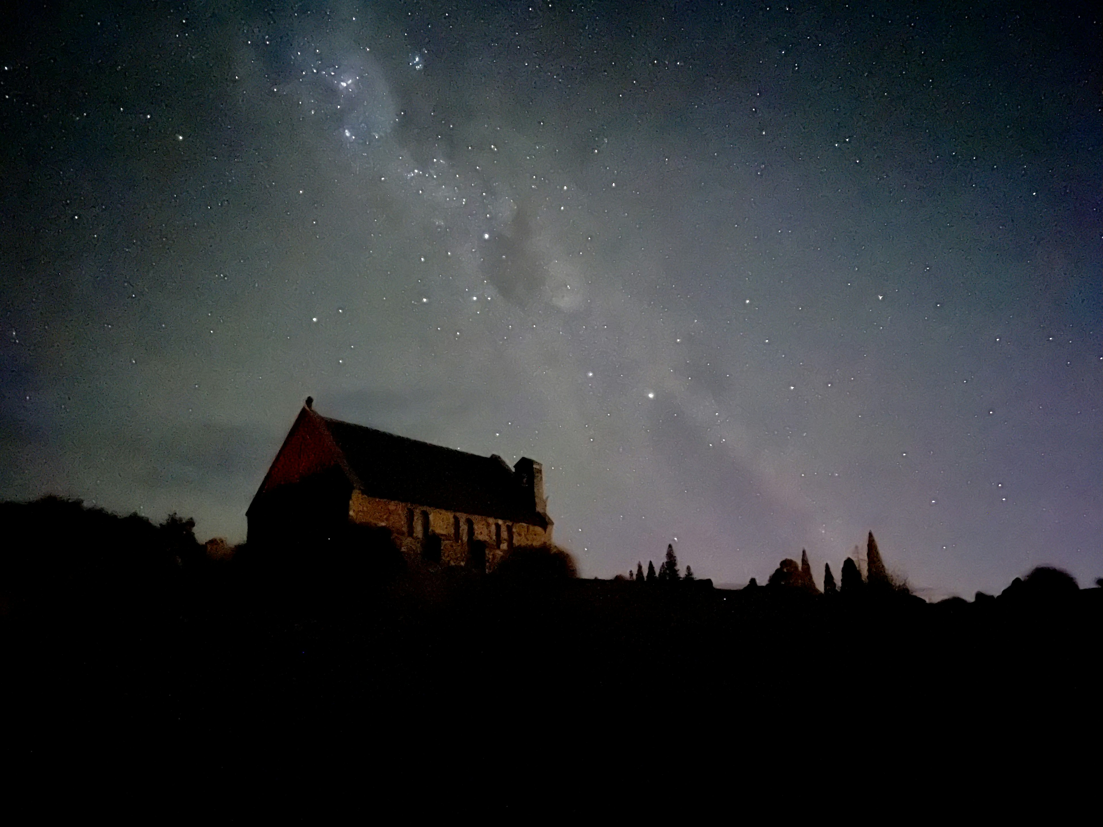 夜空に広がる銀河と星々の下に立つ静かな家