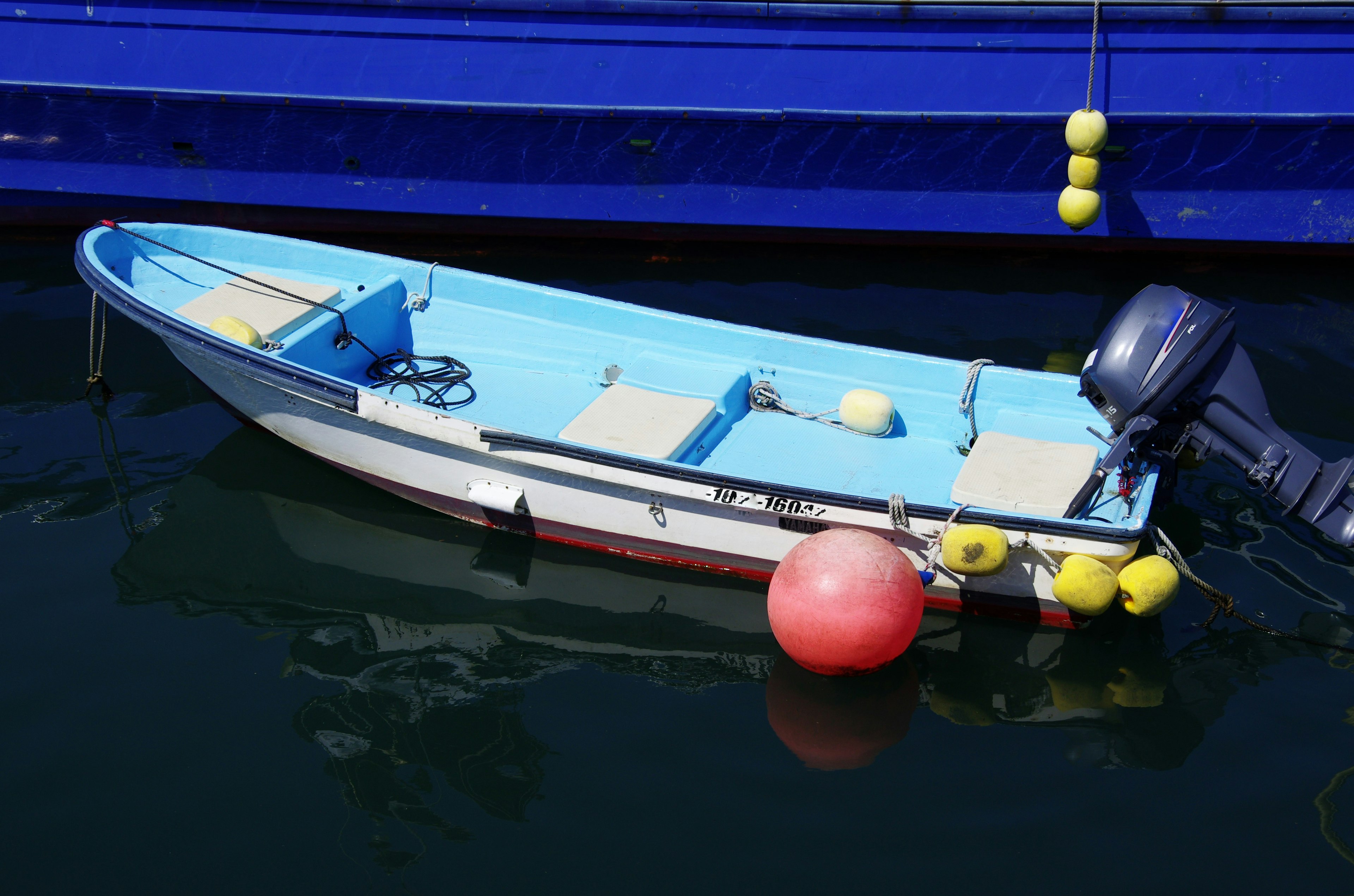 Una piccola barca blu con una boa rossa che galleggia sull'acqua calma