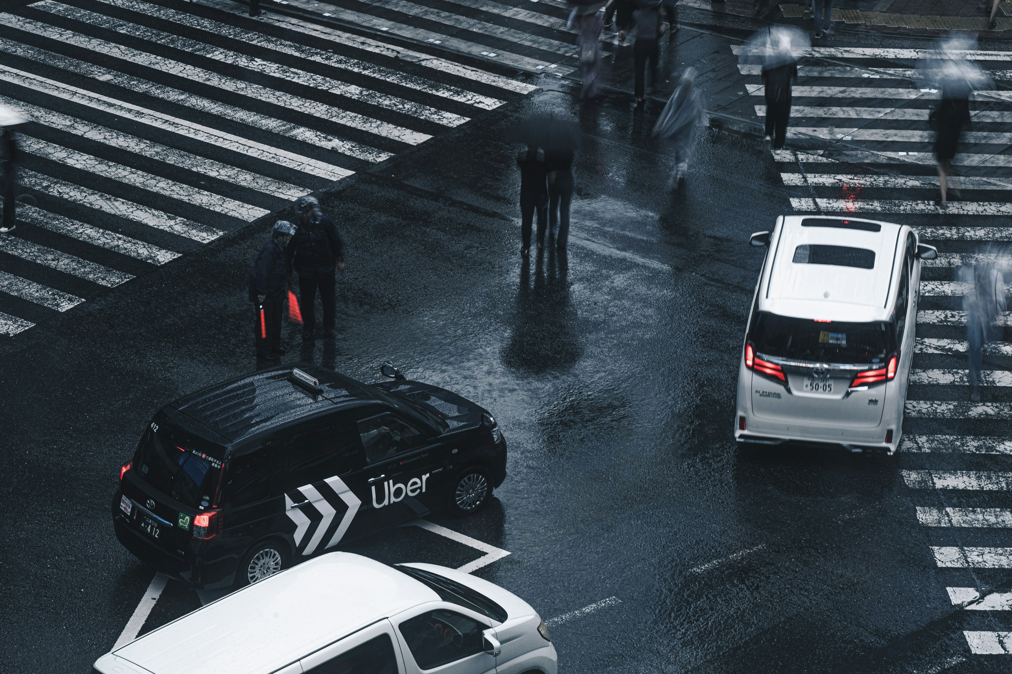 비 오는 날 보행자와 함께 횡단보도에서 회전하는 Uber 차량