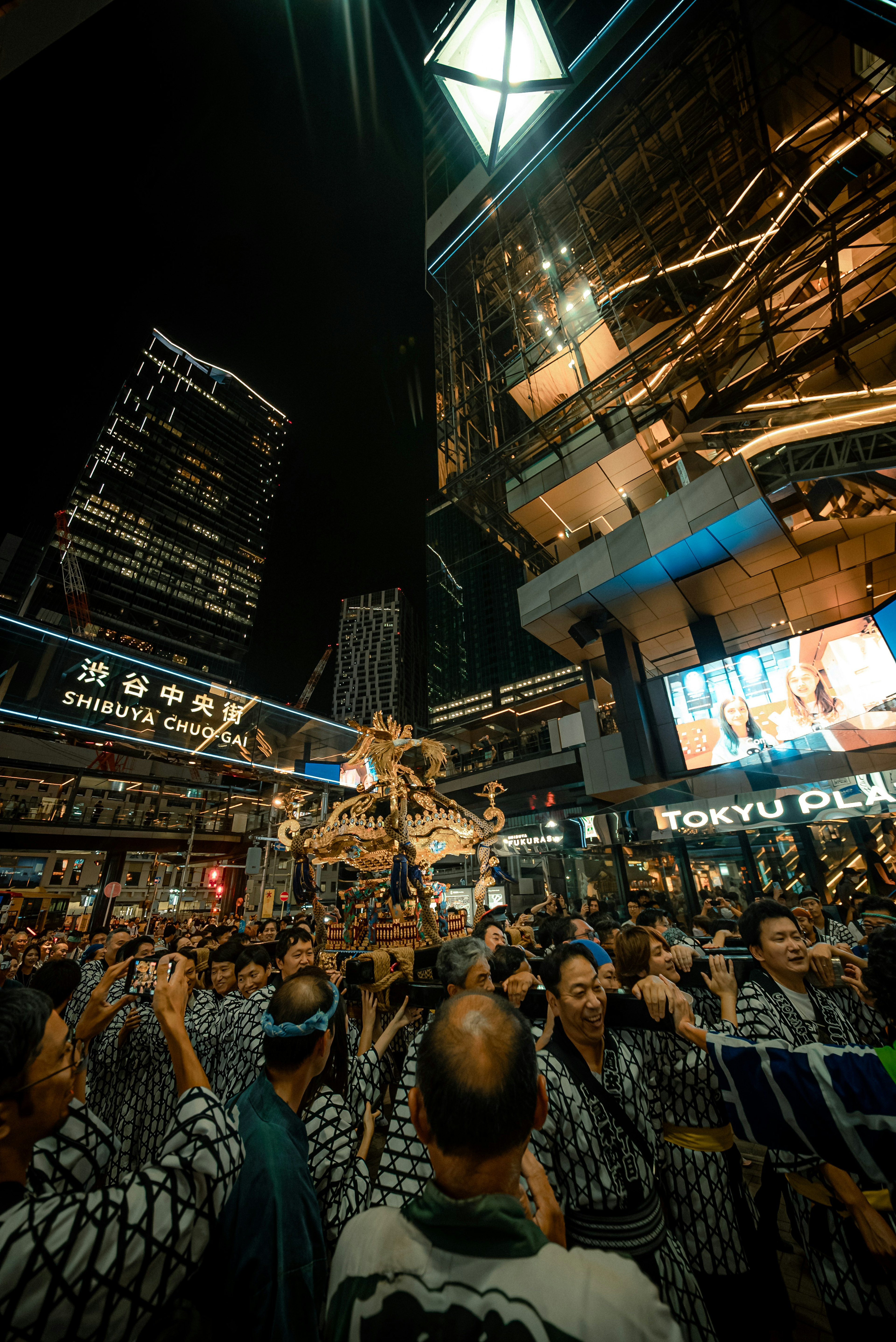 夜の都市で神輿を担ぐ人々の賑やかな光景