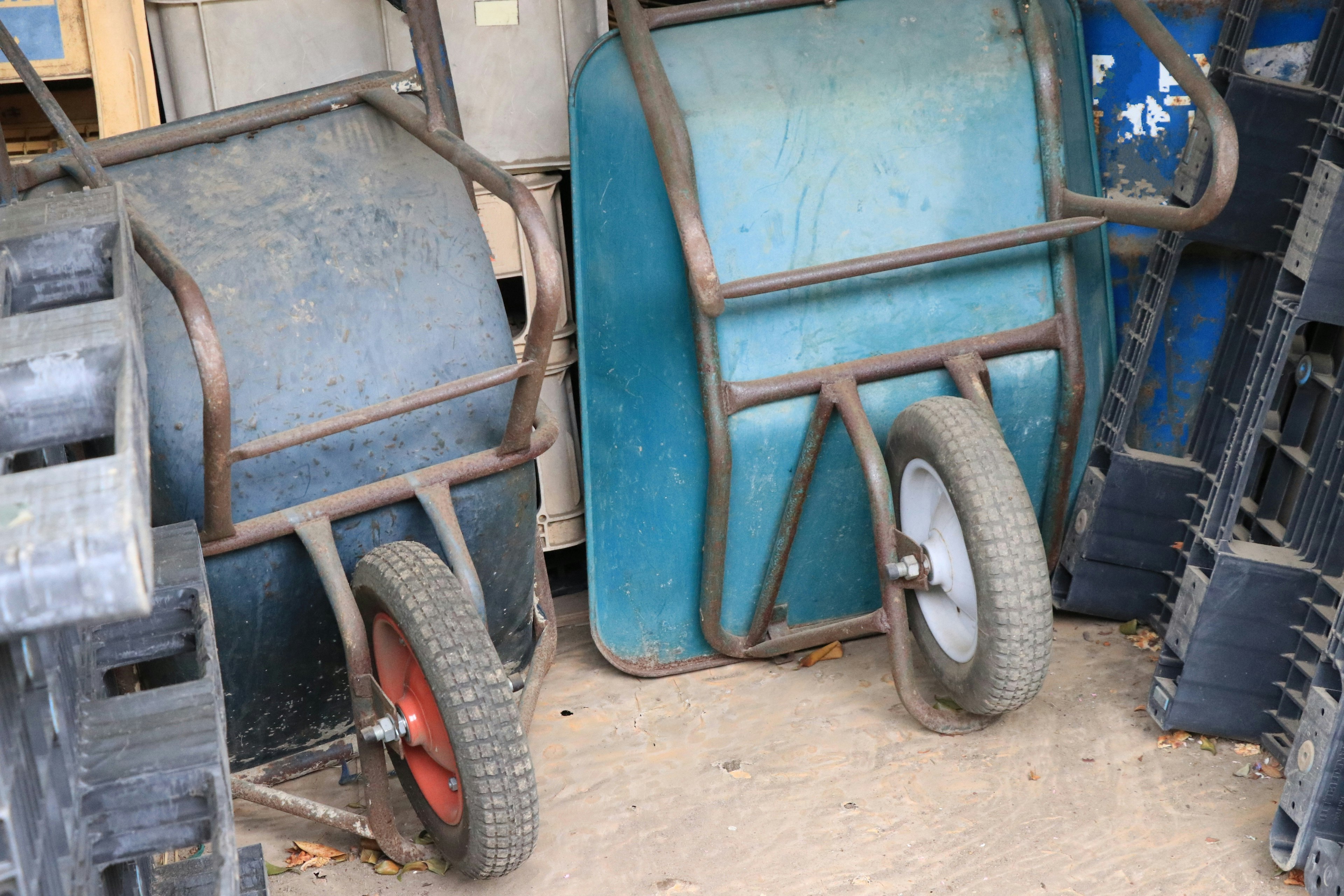 Two different colored wheelbarrows side by side